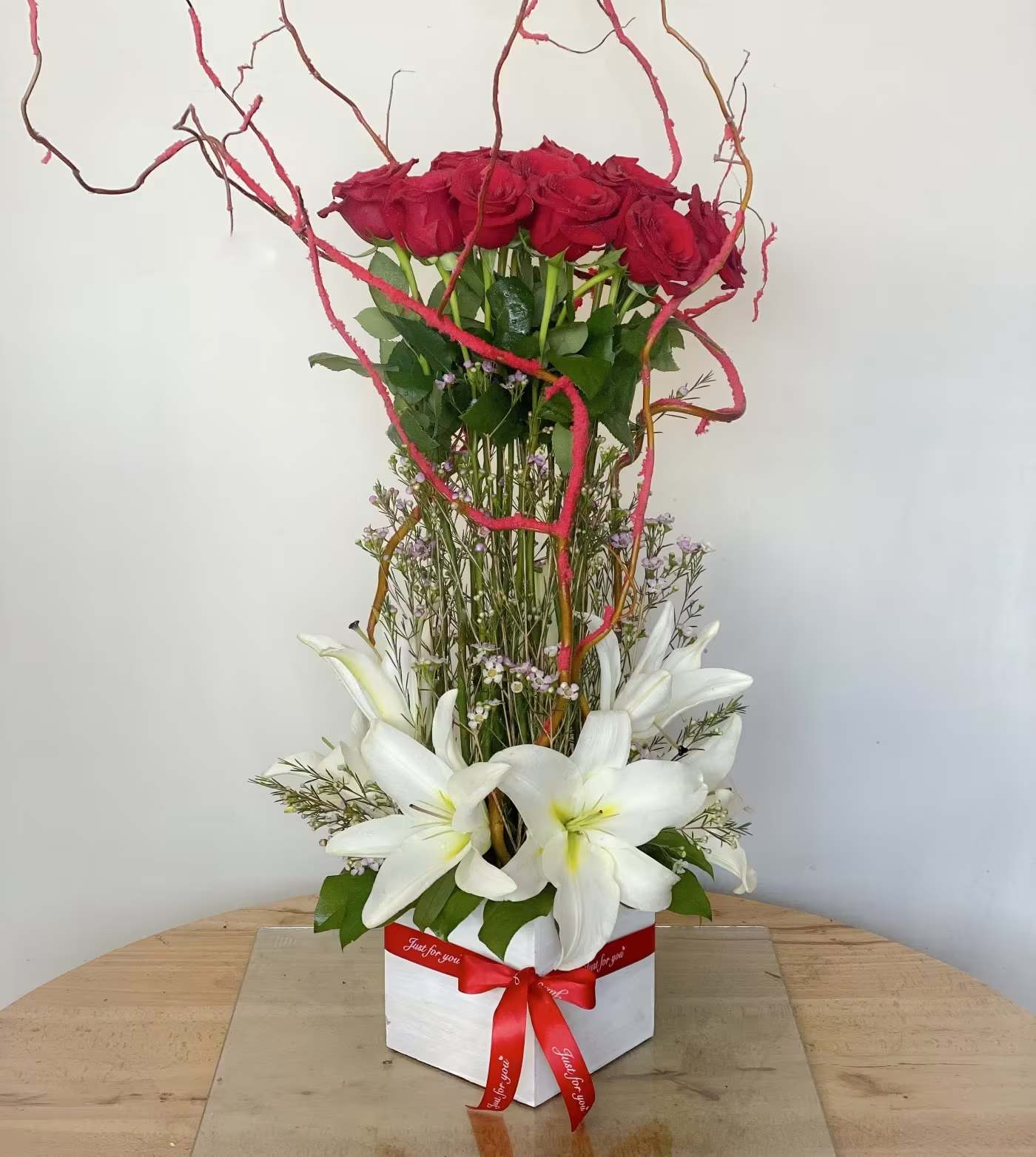 Magnificent Roses - Tall, contemporary and absolutely magnificent! This grand design of premium equadorian roses arranged with lilies and wax flower accented with curly willows is “a must” to impress the queen in your life! Designed to “WOW” and definitely a head turner!  Approximately 26” H x 10” W 