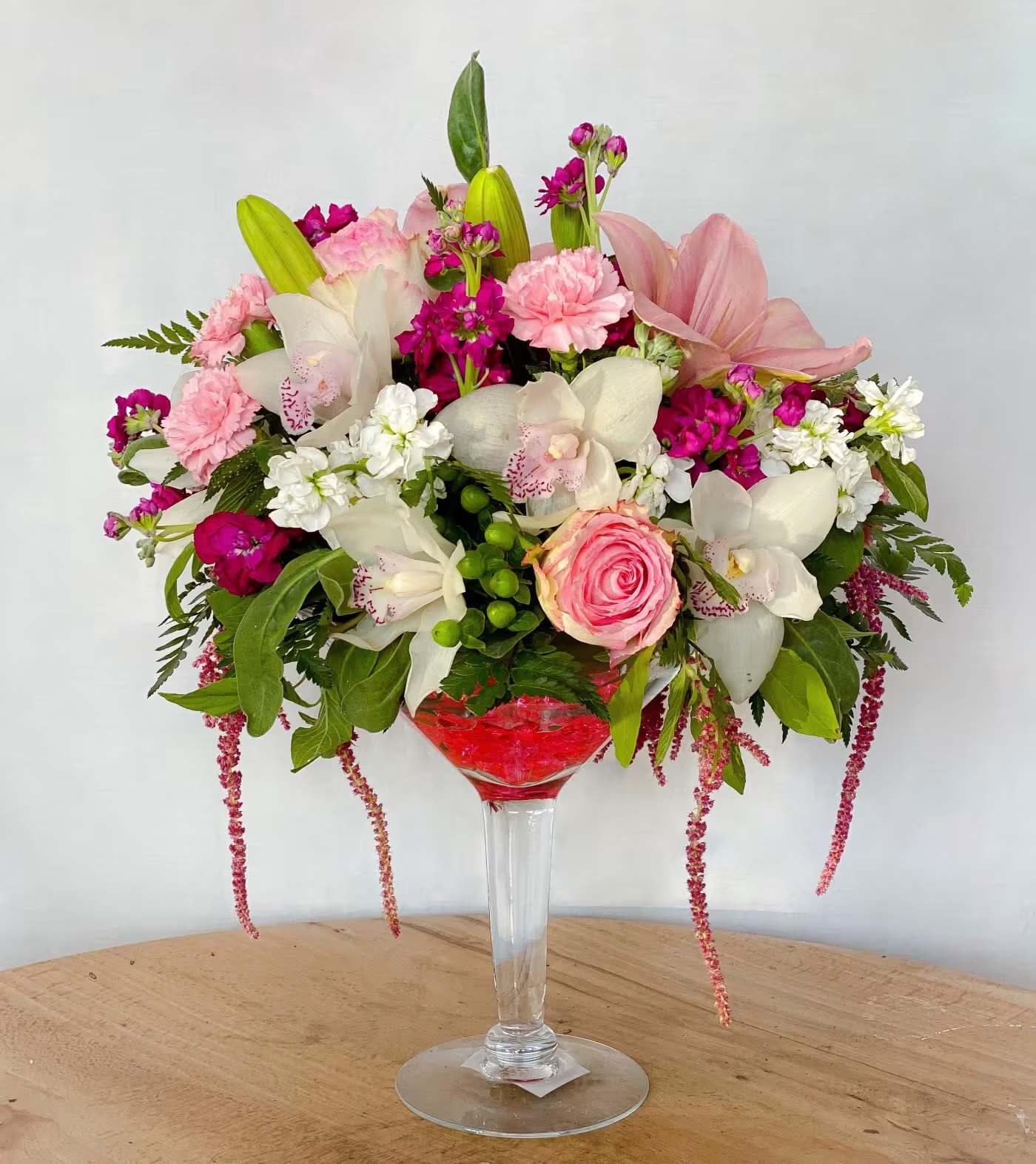 Flowers And Cocktails - When first meetings are always as exciting with a glass of martini! Connect and be remembered by sending this unique and stunning bouquet of fresh spring mix of Ecuadorian roses, cymbidium orchid, lilies, daisies and dianthus accented with hypericum, berries, montecasino and cascading amaranthus arranged in a keepsake martini glass. A second date in the works, I guarantee it!  Also great for Birthdays, Anniversary, Women’s Day, Mother’s Day, Breast Cancer Awareness Day or Just Because you remembered. Order for same day delivery today!  Approximately 15&quot; H x 12&quot; W 