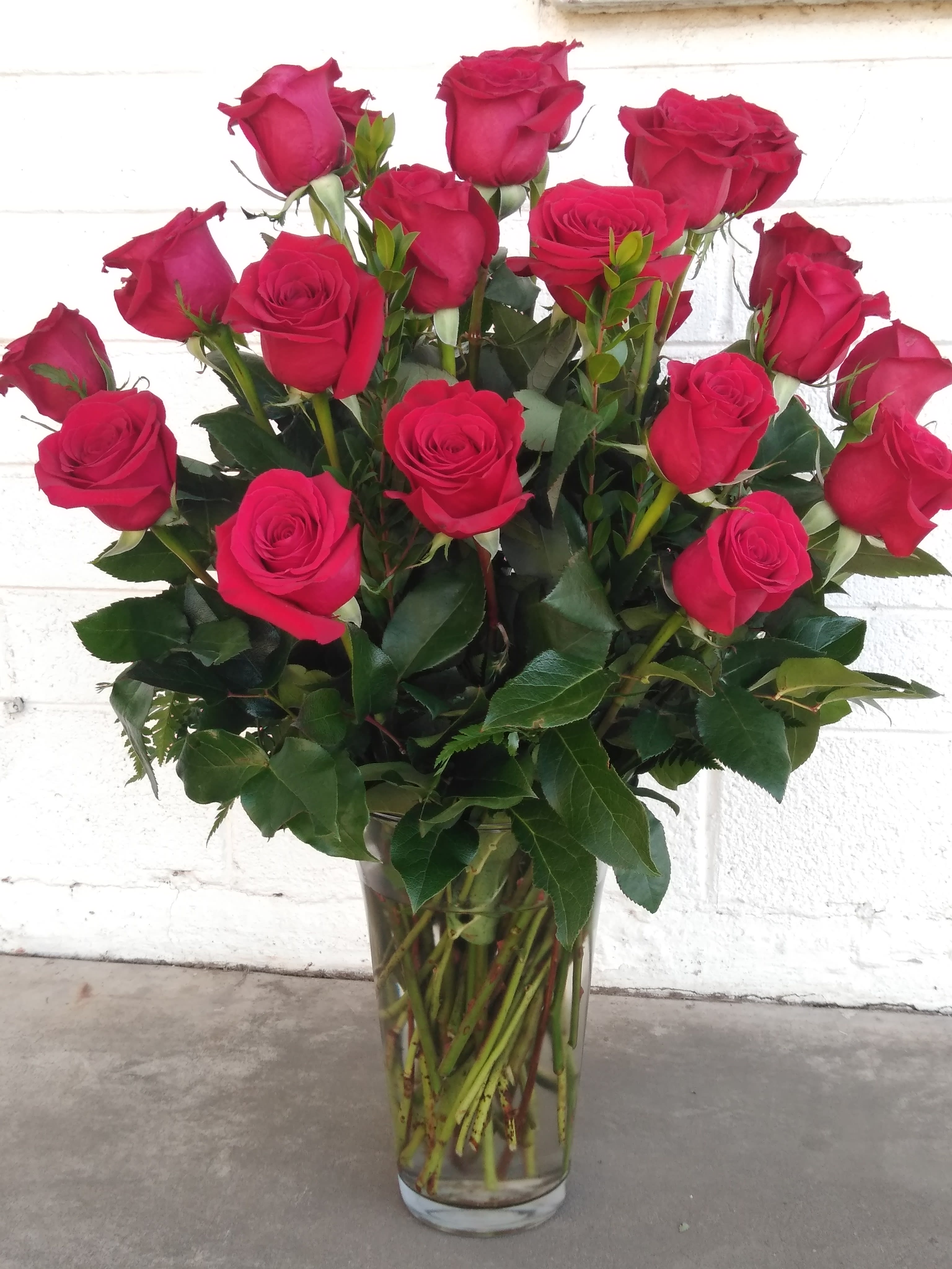True Romance Roses by Blooming Canyon - Beautifully arranged 2 dozen long-stemmed roses with greenery in a clear vase