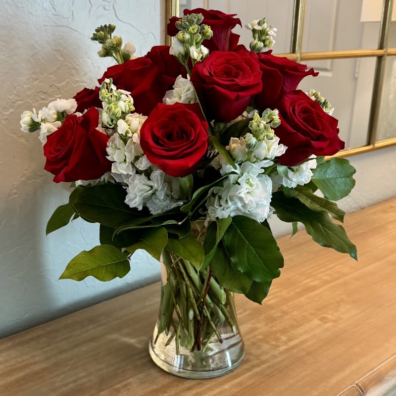 Dazzling Dozen - The Dazzling Dozen is sure to wow your special someone! One dozen vibrant red roses with white stock and seasonal greenery make this arrangement something she'll love! A great Valentine's Day gift or just to say I Love You!