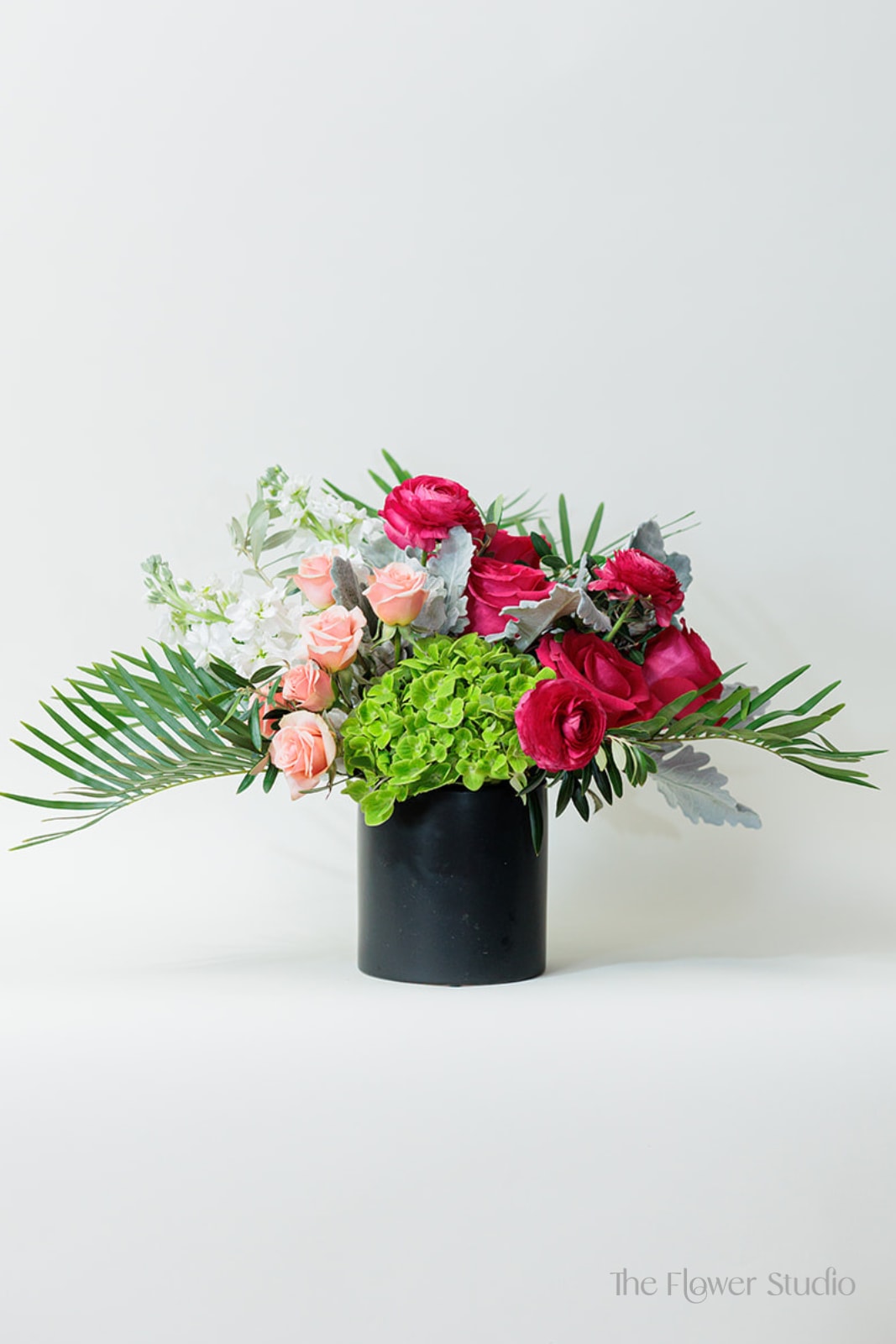 Evelyn Evelyn - This stunning floral arrangement combines bold, vibrant colors with soft, romantic tones, creating a captivating and elegant design. Together, these flowers and foliage create a harmonious blend of bright, lively colors and soft, subtle accents, perfect for adding elegance and charm to any occasion. Approx. Approx. H14” x W21”