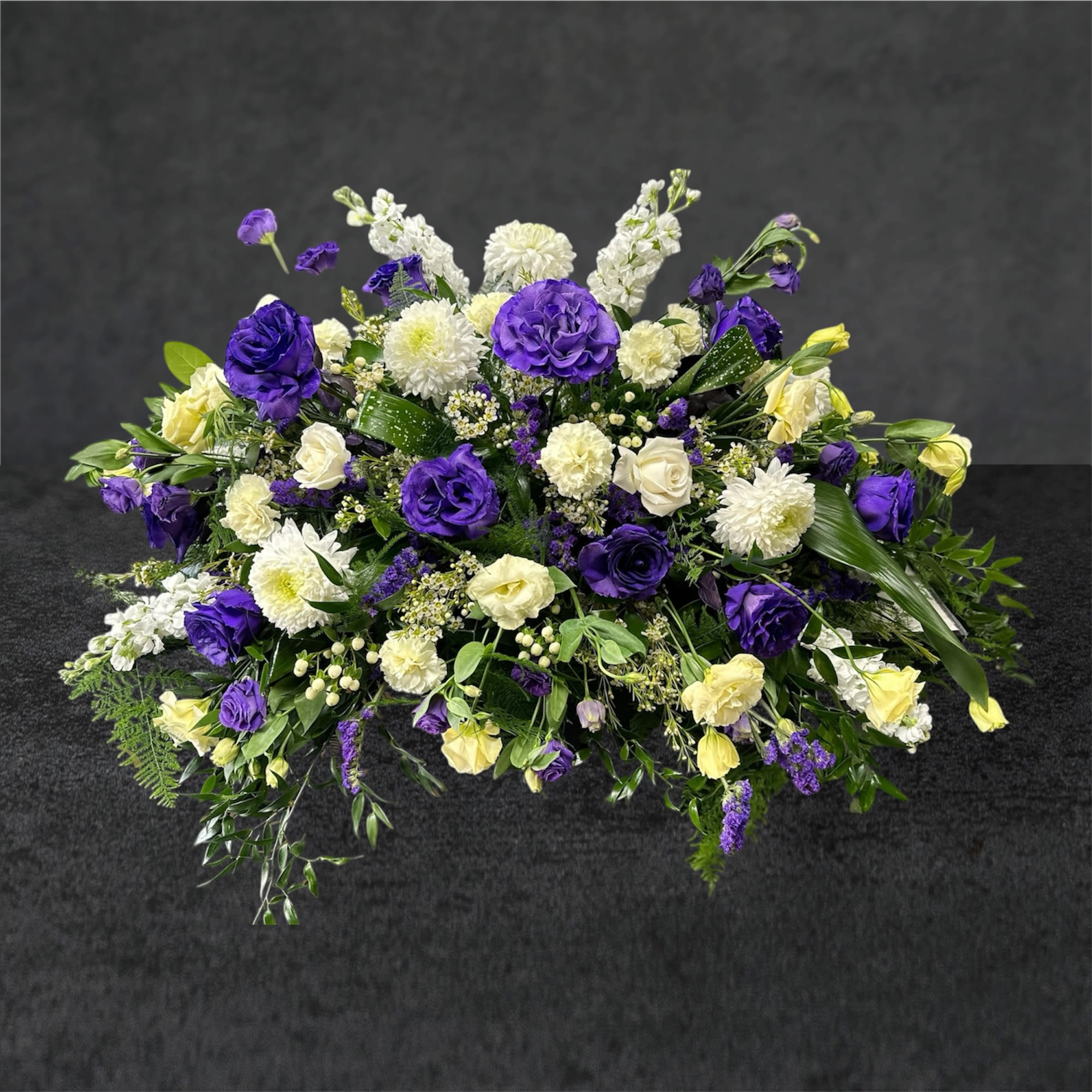 Purple Paradise Purple Paradise - A casket spray is a beautiful floral arrangement designed to adorn the top of a casket during a funeral or memorial service. It is a heartfelt tribute to honor the deceased and comfort grieving loved ones. **Features:** - Customizable designs to reflect the personality and interests of the deceased. - A variety of flower choices, from classic roses to seasonal blooms. - includes greenery and other accents for a lush and vibrant look. **Benefits:** - Enhances the overall atmosphere of the service, offering a visual representation of love and remembrance. - Provides a sense of peace and beauty during a difficult time. - A personal touch that can celebrate the life and spirit of the individual. **Ordering:** When ordering a casket spray, consider the preferred colors and types of flowers that represent the deceased's personality or favorite blooms. Our Florists can work with you to create a stunning tribute that honors their memory. A casket spray is not just a floral arrangement; it's a heartfelt expression of love, making the farewell a little more beautiful.