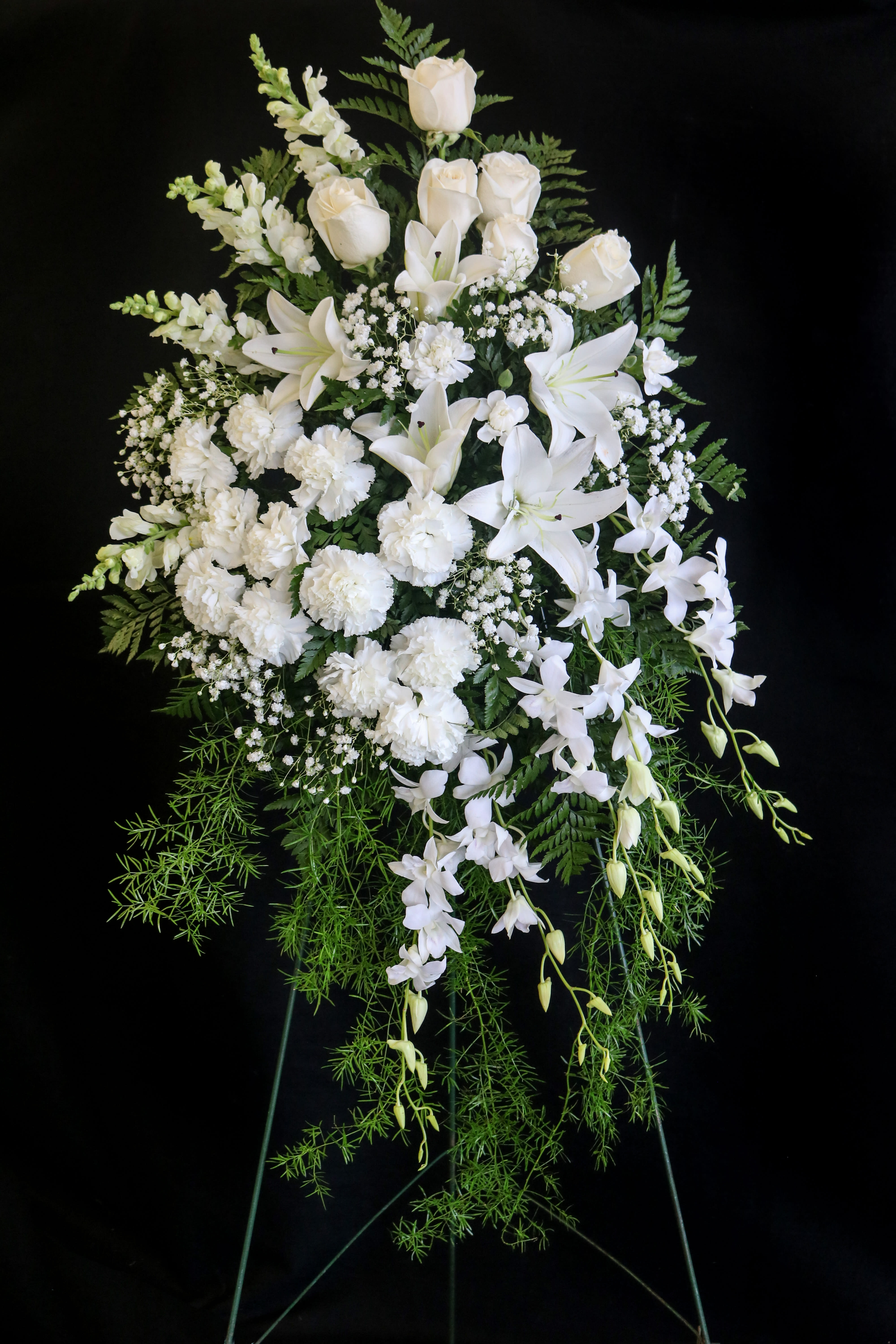 Flowing White Spray Flowing White Spray - An elegant white spray featuring lilies, roses, dendrobium orchids, carnations, and snapdragons arranged in a graceful shape.