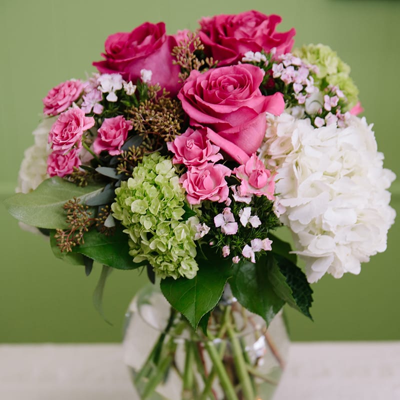 PINK EMBRACE PINK EMBRACE - Embrace their heart with a beautiful display of hot pink roses , white hydrangeas, green hydrangeas, pink mini carnations , seeded eucalyptus all arranged in a clear ginger vase.