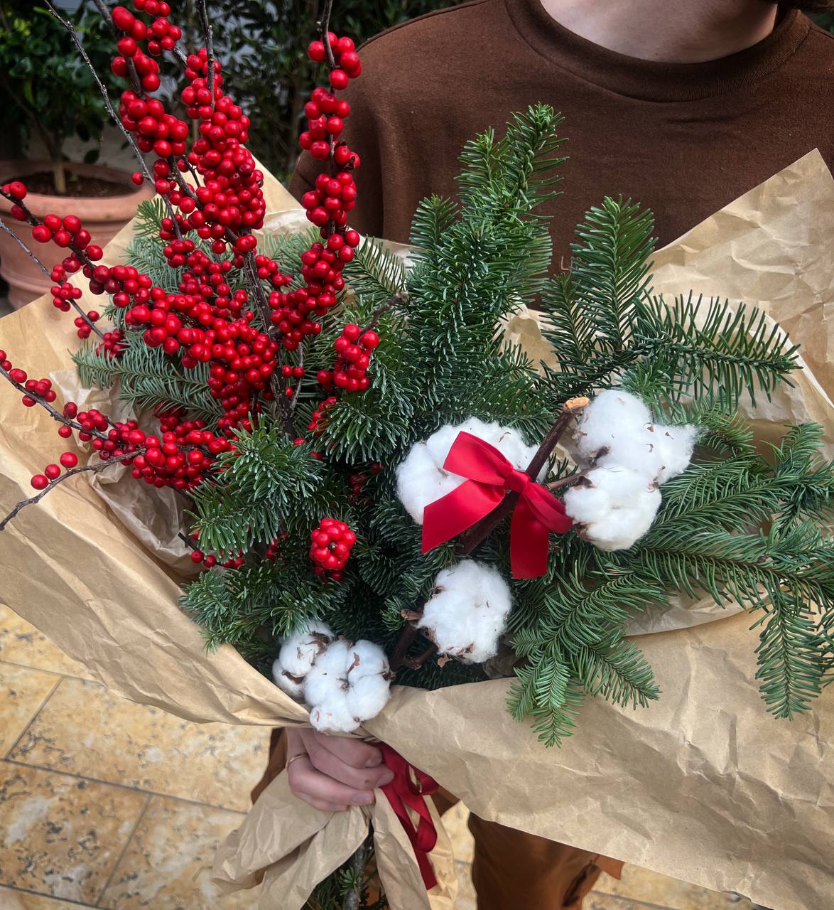 Christmas Whisper Christmas Whisper - Christmas Whisper – a charming bouquet that captures the essence of the holiday season. Lush evergreen branches fill the air with the fresh scent of winter, while delicate cotton flowers add a touch of softness and warmth. Vibrant red berries bring a festive pop of color, beautifully complemented by a classic red ribbon. Perfect as a holiday gift or a cozy home decoration, this arrangement embodies the magic and elegance of Christmas.