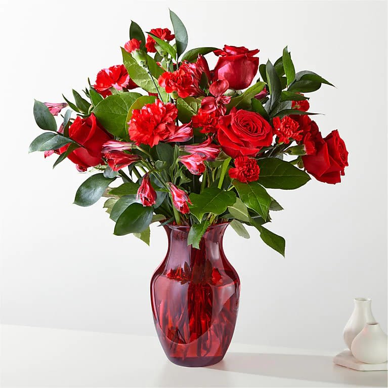 The Heartstrings Bouquet - Amplified by a ruby red vase, this rich arrangement of roses, carnations, and Alstroemeria is like playing them a love song.