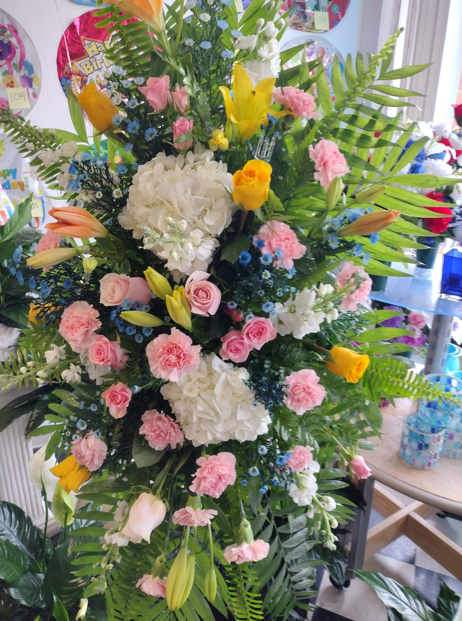 Special Moments Special Moments - Beautiful standing spray with hydrangeas, pink/yellow roses, pink carnations, yellow lilies, blue mums, and plenty of lush greenery make this a one of a kind.