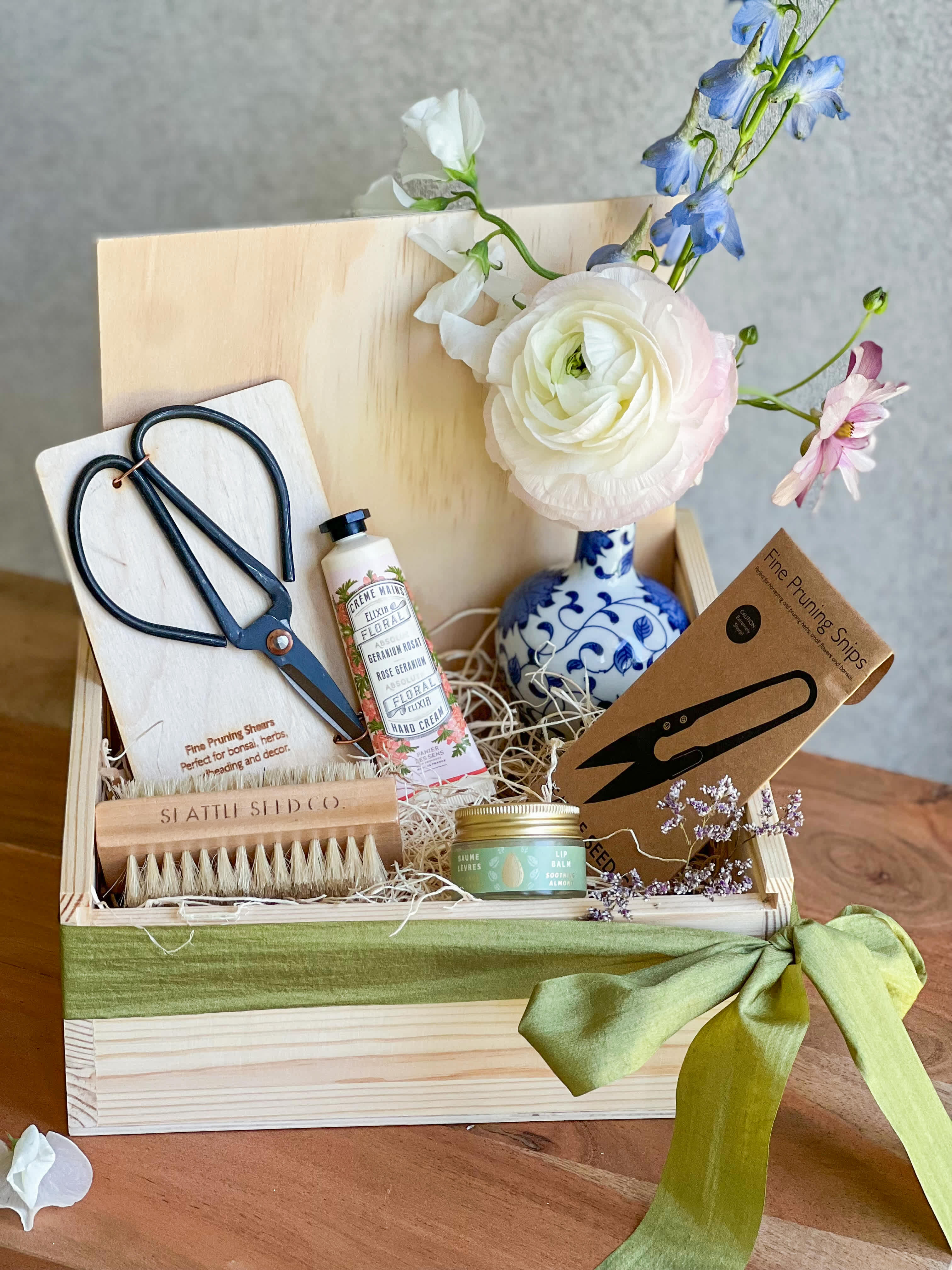 The Garden Box The Garden Box - A wooden keepsake box, a hand cream by panier de sens, a seasonal bud vase arrangement, pruning shears, nail/ vegetable brush, almond lip balm, pruning snips and a hand written card.