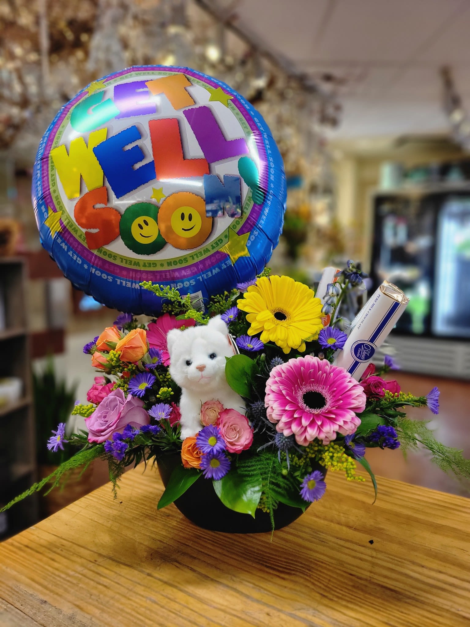 Bright Get Well Soon Arrangement - This cute arrangement comes with 3 chocolate bars, an 18&quot; get well mylar, and a cute stuffed animal. 