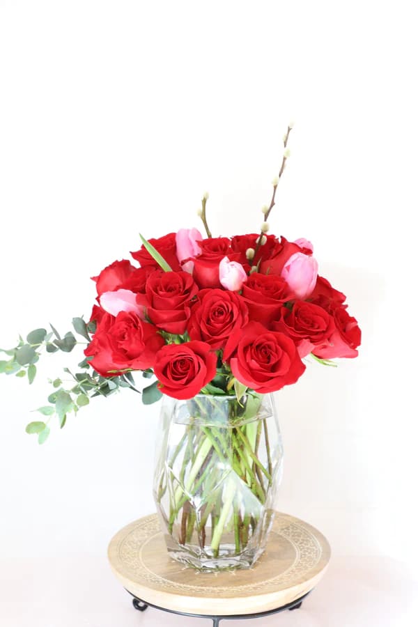 Romantic Rose - A gorgeous, compact arrangement with perfectly bloomed roses and pink tulips scattered about with minimal greenery in a modern, geometric glass vase.  Standard size approximately has a dozen roses. Deluxe size approximately has two dozen roses. Premium size approximately has three dozen roses.