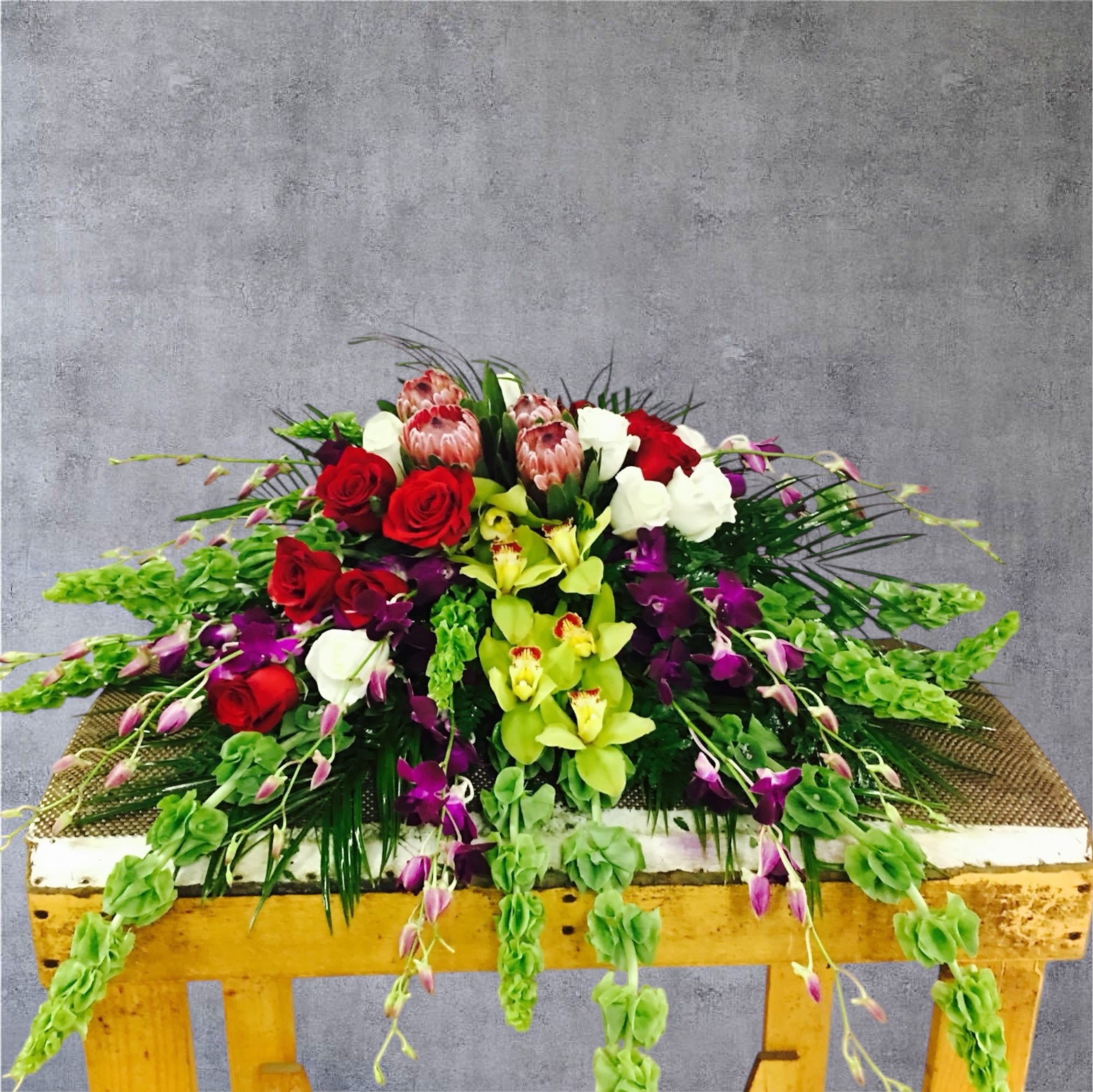 Dream in Color - Casket spray with vibrant colors and exotic orchids.