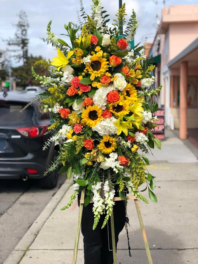 Yellow, orange &amp; white sympathy spray.  - This spray includes sunflowers, roses, spray roses, lilies, snapdragons, &amp; other filler flowers to compliment the color scheme. 