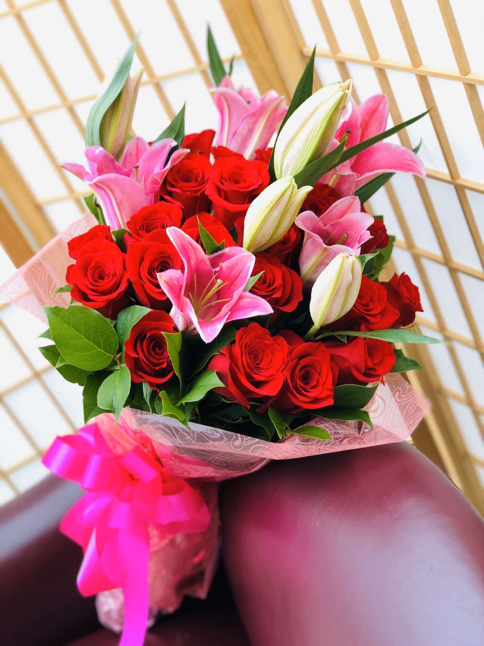 Red Roses and pink lilies - 24 red roses,5 pink lily stems, beautifully wrapped with a large bow 