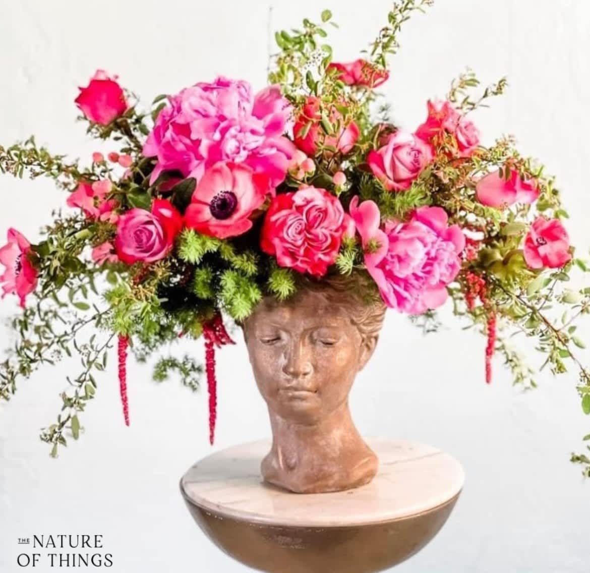 Ivy - Perfectly pink, these gorgeous seasonal florals are artfully designed in our signature lady head bust. Certain to impress, this keep sake vase is guaranteed to be one of a kind!  Flowers and greenery may vary due to seasonal availability, but that’s part of the charm! Our creative designers will substitute with the freshest high end product available- some grown in our very own garden!- and create something beautiful.  *Have a special request?* Let us know in the special instructions section during checkout.