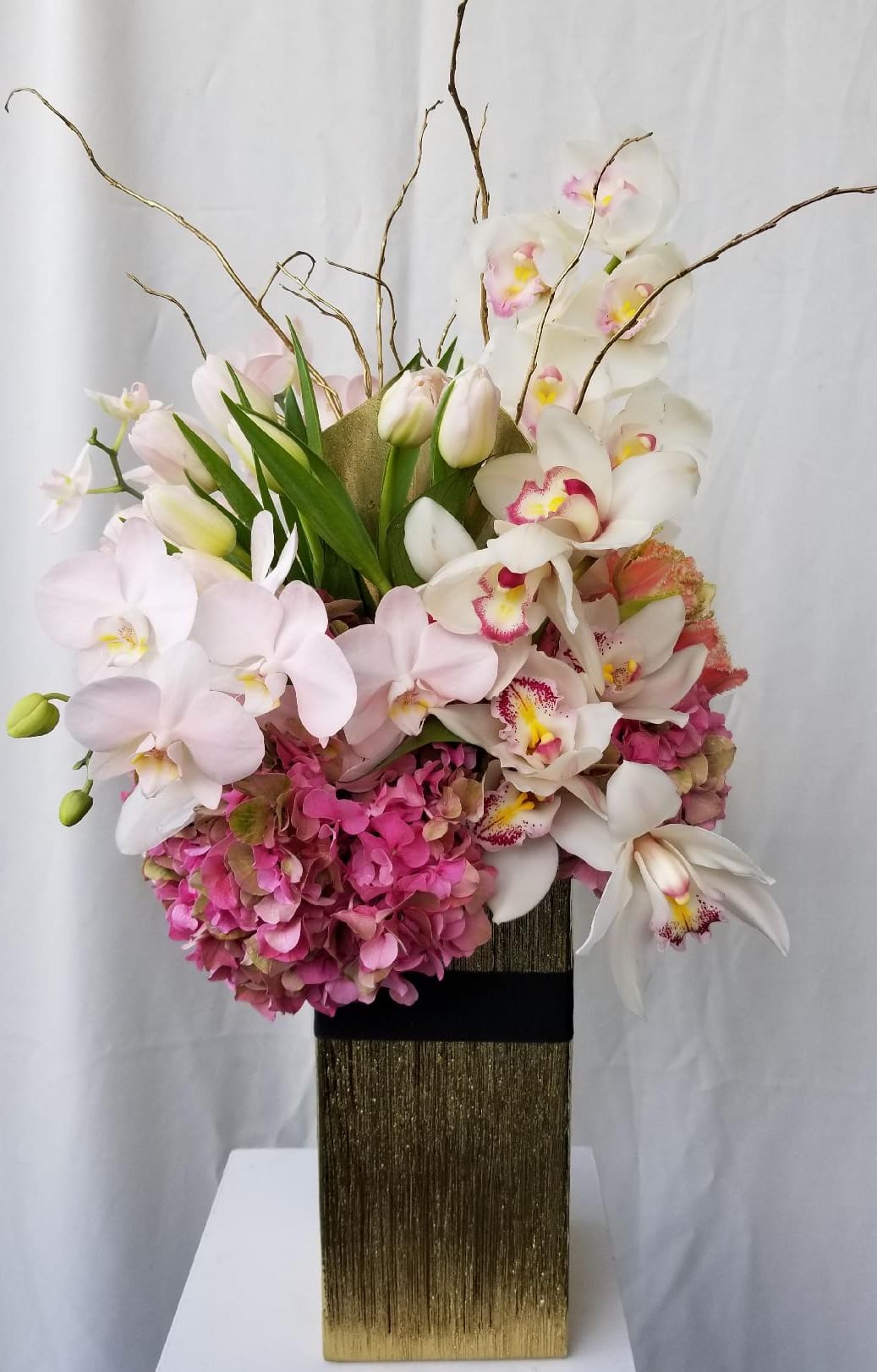 Eccentric Taste -  Embrace the delightful eccentricity of our artistic floral masterpiece, crafted to stand tall and capture attention. This enchanting arrangement showcases the beauty of pink hydrangeas, gorgeous cymbidium orchids, and white tulips, crowned with the graceful touch of curly willow branches.  At Dave's Flowers, we take pride in creating unique and visually stunning arrangements that transcend the ordinary. Elevate your space with this exquisite blend of colors and textures, perfect for any occasion that demands a touch of creativity.  Explore the artistry of our floral designs, meticulously curated to bring joy and beauty to your surroundings. Delight in the unexpected with our delightful arrangement featuring pink hydrangeas, cymbidium orchids, and white tulips. Make a statement with nature's wonders at Dave's Flowers, where floral artistry meets passion.