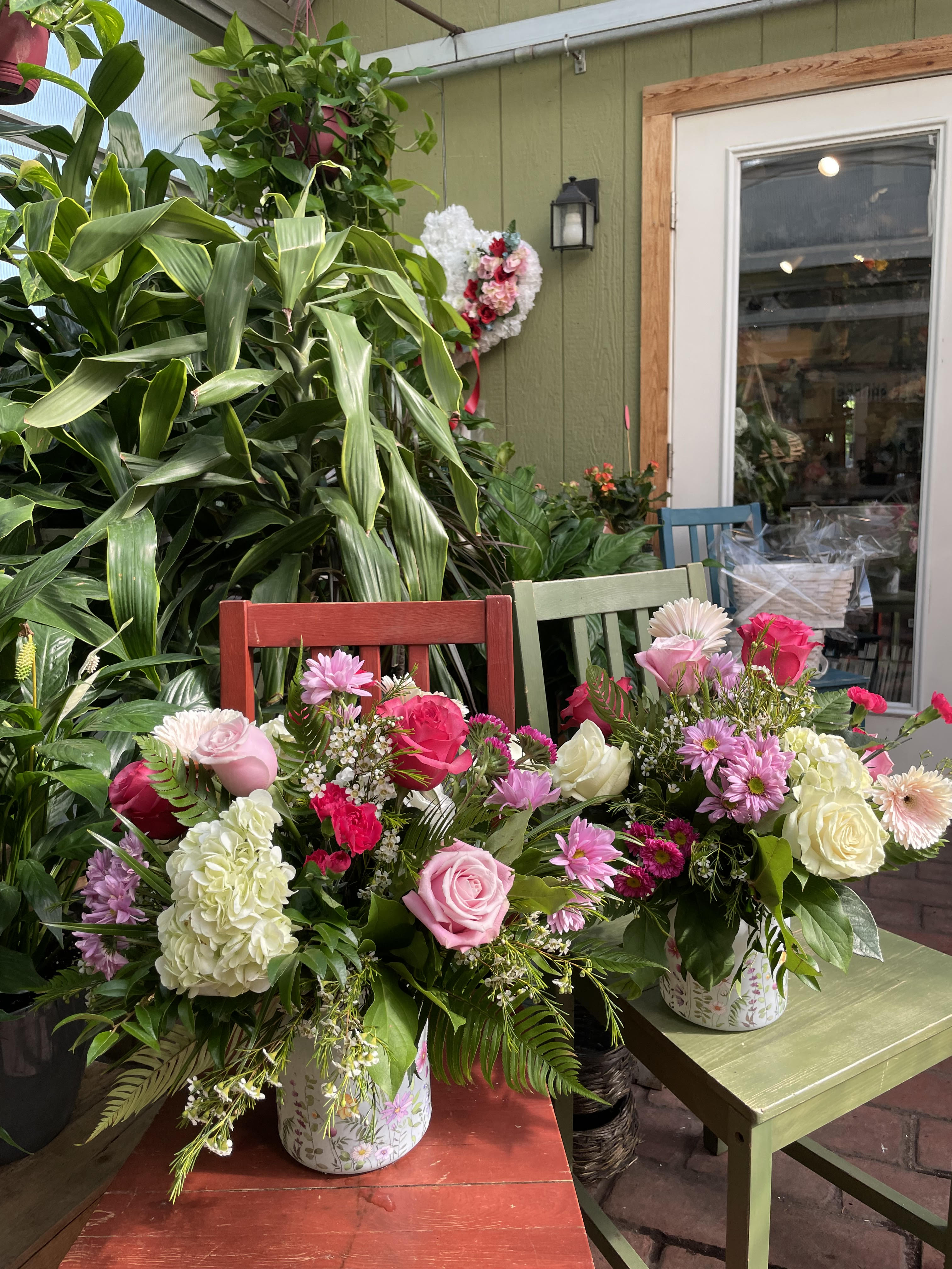 Mamma Mia  - Gorgeous pink or purple roses, blue delphiniums, green hydrangeas, lambs ear, and wax in a keepsake vase give this arrangement a walk through the garden look. 