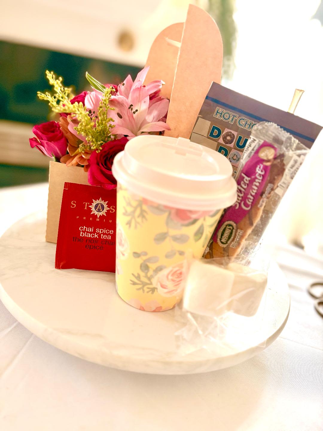 Flowers and Goodies Gift Set - Feast your eyes on this fun filled treat of Fresh cut Blooms and sweets in a handheld caddy.  It includes a mixed bouquet, hot chocolate pack, marshmallows, chai tea, honey and a delightful biscotti biscuit with a hot cup for preparation.  This will definitely change someone's day for the better and let them know they are appreciated.  Perfect for Birthdays, Mother's Day, Easter, International Women's Day, Breast Cancer Awareness Day, Administrative Assistants Day or Just Because.  