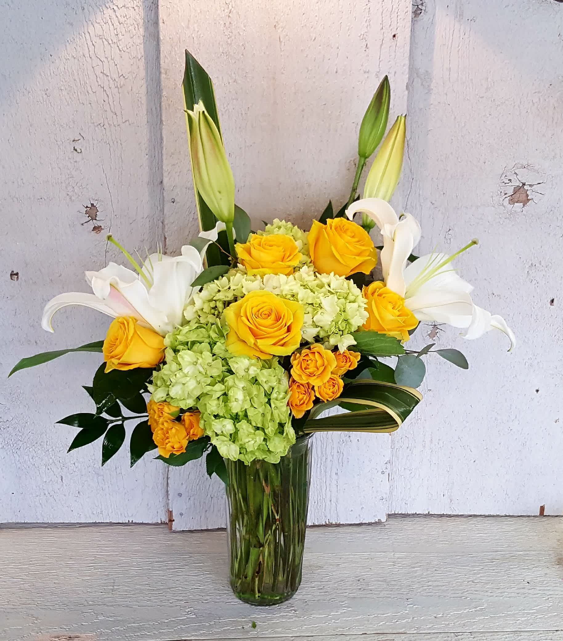 On The Brightside On The Brightside - A sure way to add a smile and sunshine to someone's life. Yellow roses, fragrant lilies and hydrangea tastefully designed in a tall vase