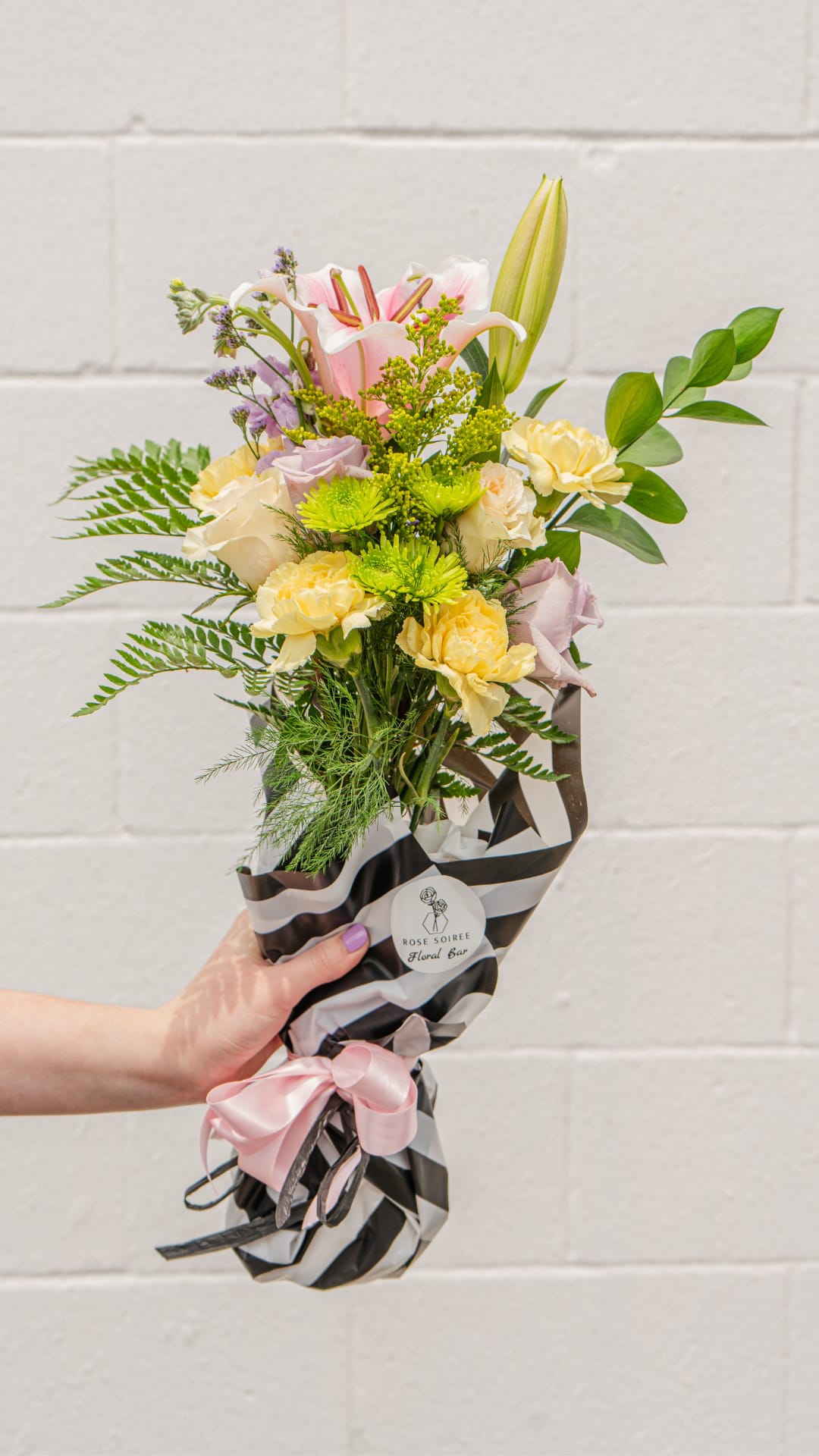 From the Garden Handtied bouquet - This handtied bouquet is a mixture of colorful flowers and greenery in seasonal shades. A self-sustaining water source is also provided with our signature florists paper making it the perfect gift for a loved one, friend, or for date night! May include but not limited to roses, spray roses, lilies, stock, chrysanthemums, alstromeria, assorted fillers and greenery.