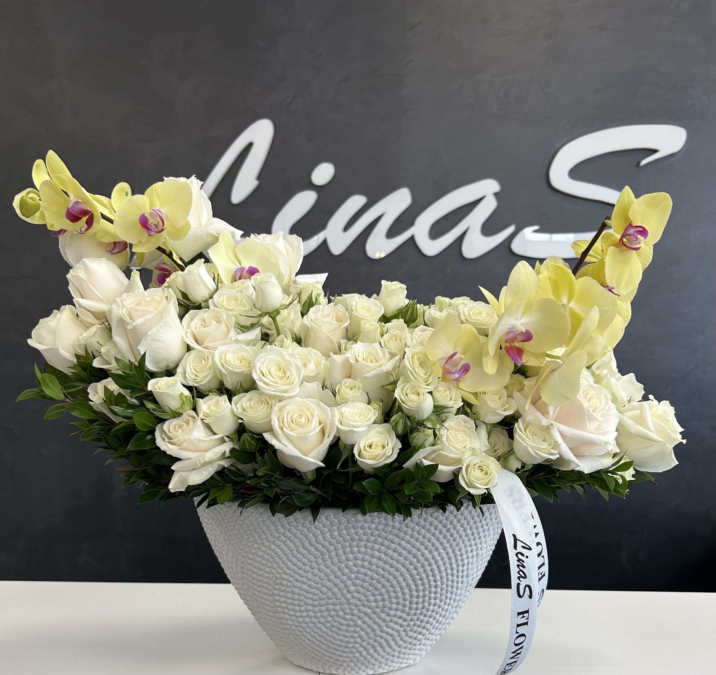 Malu white Malu white - White roses symbolize purity, elegance, and new beginnings, while green Phalaenopsis orchids represent renewal, harmony, and prosperity. Together, they create a fresh and sophisticated floral arrangement, perfect for conveying peace and timeless beauty.