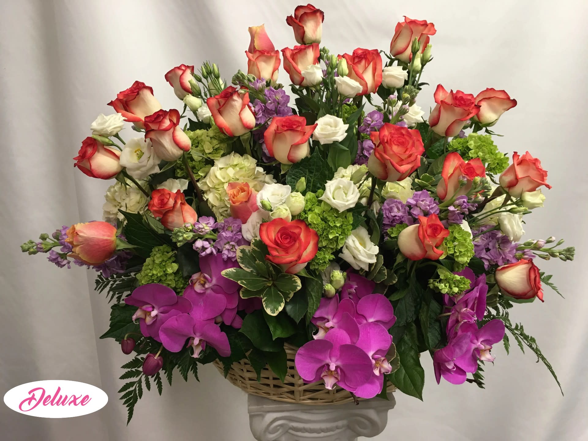 Loving Tribute Basket  - This arrangement is in a lovely wicker basket and designed round and full. With all roses and touched with orchids and other seasonal flowers it make for a beautiful piece that the family can take home as well. 