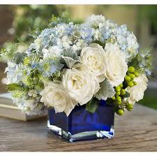 Blue Blooms Cube - Cube centerpiece vase arrangement with beautiful blue hydrangeas, clustered white roses, green hypericum berries and more.