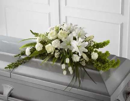 The Resurrection Casket Spray - The Resurrection Casket Spray inspires thoughts of comfort and peace to those wishing to pay their respects for the loss of the deceased. White tulips, roses, snapdragons, Oriental lilies, larkspur, carnations and Monte Casino asters are accented by the bright green stems of Bells of Ireland and an assortment of the finest lush greens to create the perfect arrangement to display on the top of their casket during their final farewell service. Approximately 40&quot;W x 24&quot;D.