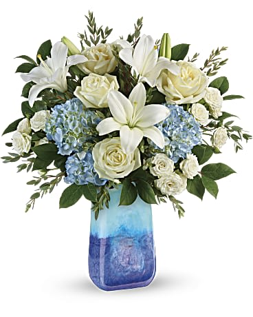 Ocean Sparkle Bouquet - DESCRIPTION VASE SIZES  Capture the magic of the sparkling sea with this soothing bouquet of blue hydrangea and white roses, artfully arranged in a breathtaking, hand-blown art glass vase that will remain a décor favorite for years to come!   This beautiful bouquet includes blue hydrangea, white roses, white spray roses, parvifolia eucalyptus, and lemon leaf.  Delivered in Our  Blue Lapis Gemstone Art Glass vase. 