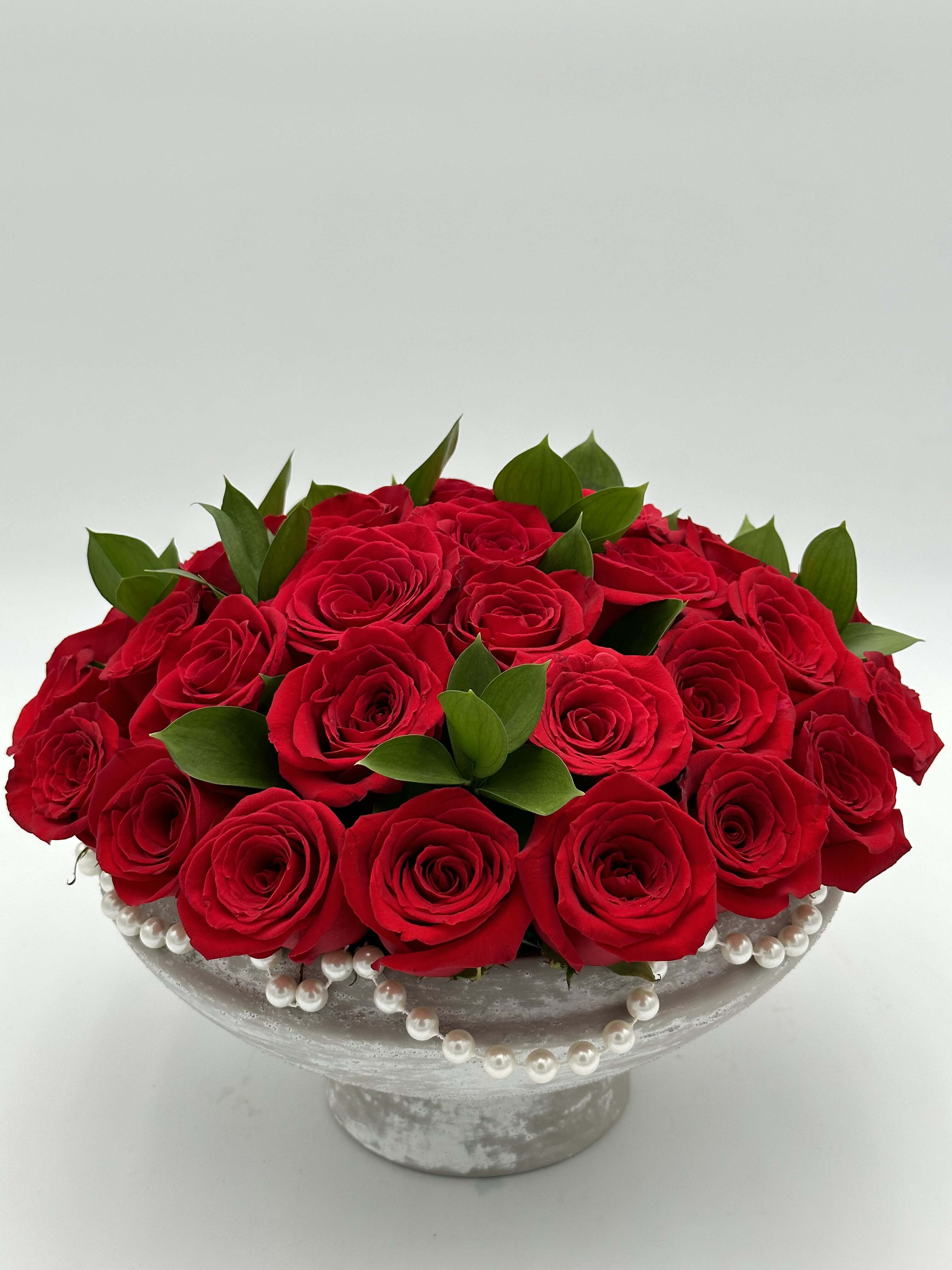 Pearl Rouge Affair Pearl Rouge Affair - A minimalistic, classy, and sophisticated arrangement that seamlessly blends the timeless allure of red roses with delicate pearl accents. In this curated ensemble, each crimson rose stands as an emblem of passion and love, while the subtle pearl detailing adds a touch of refined luxury. Ideal for enhancing home decor with a touch of sophistication,