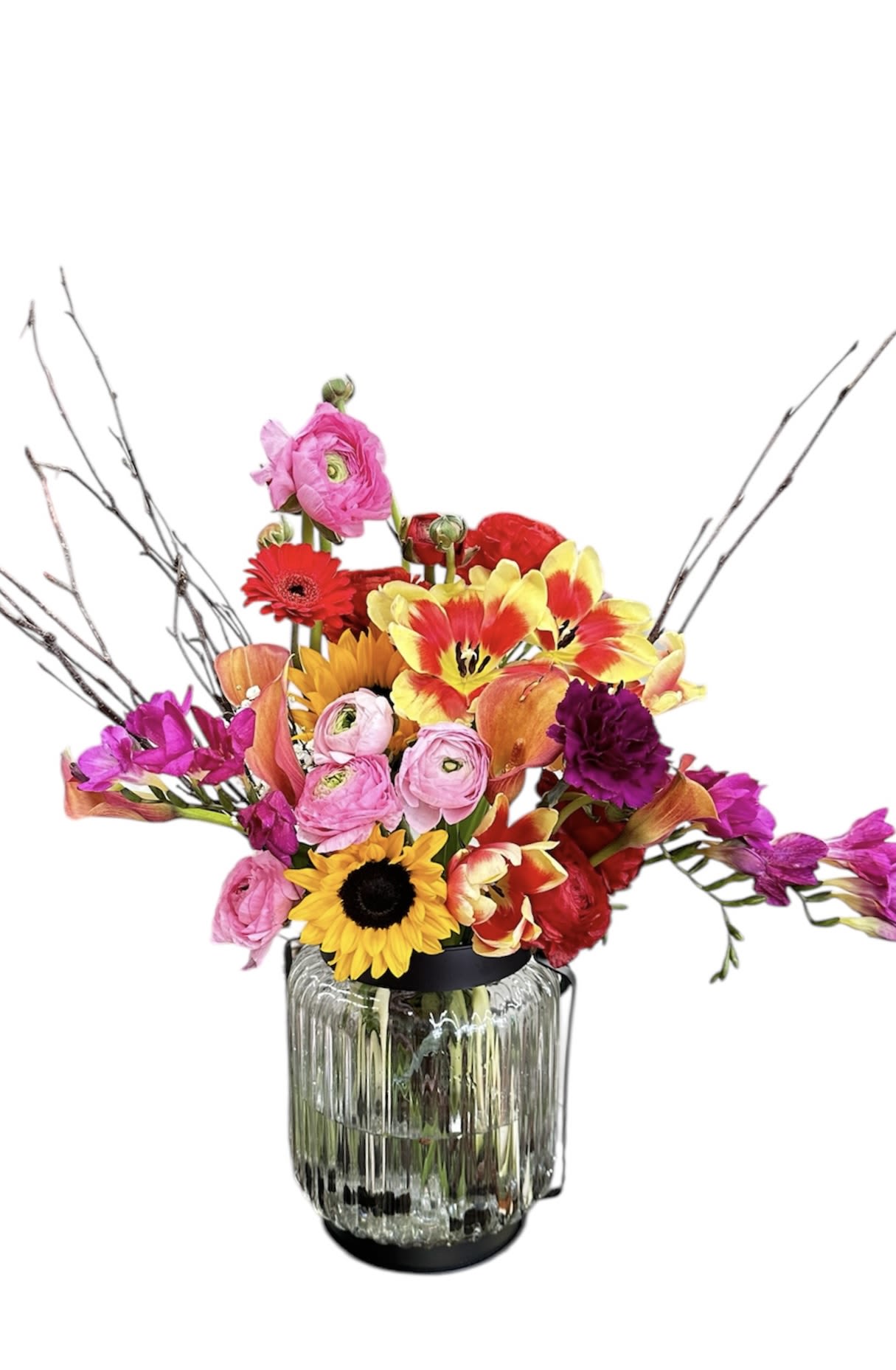 Vibrant Harmony - This lively arrangement bursts with colorful blooms, including sunflowers, ranunculus, tulips, and calla lilies, creating a stunning visual contrast. The addition of delicate branches adds a touch of rustic elegance, making it a perfect centerpiece.