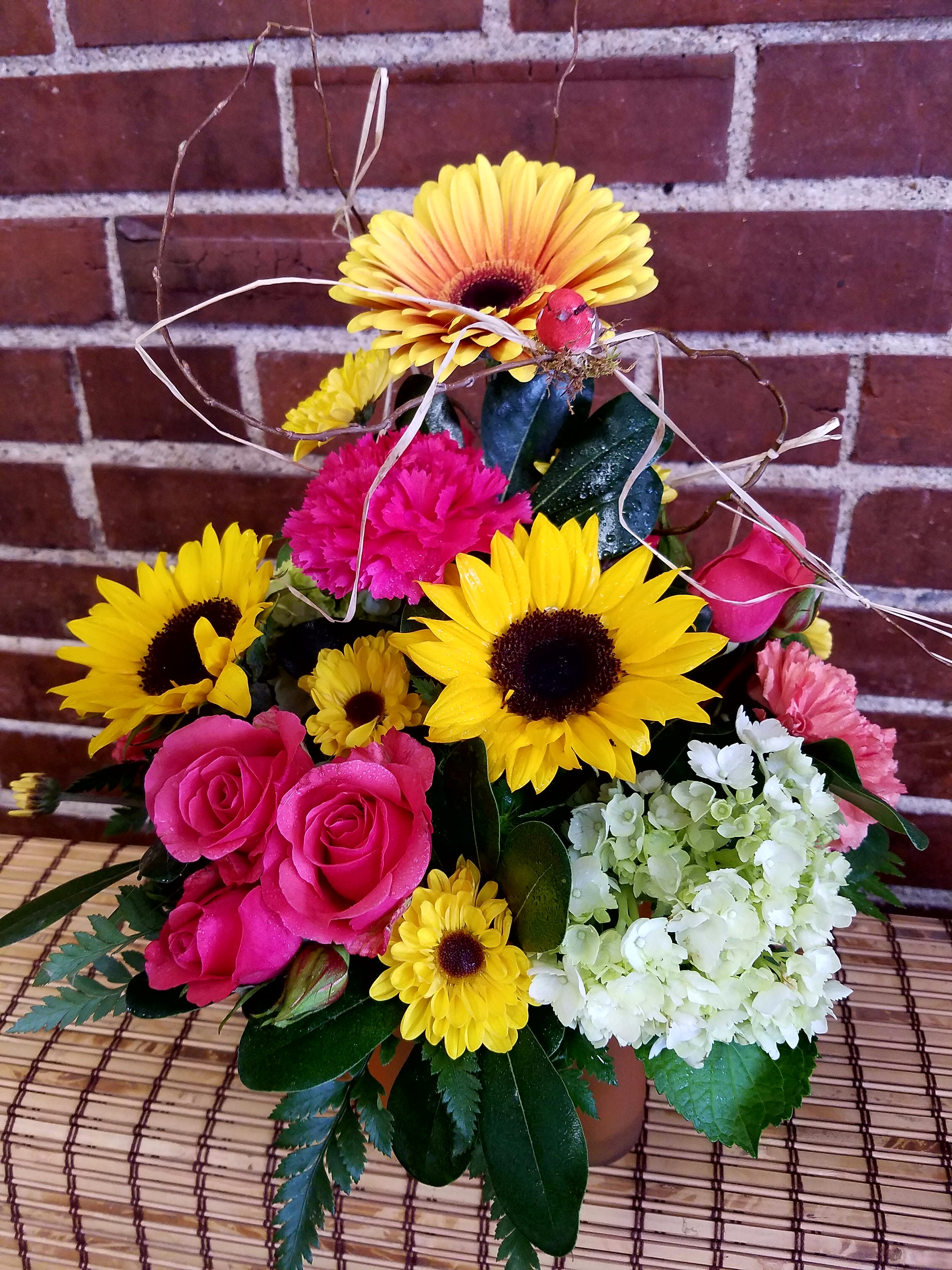 Eckert Florist's Deluxe Upsy Daisy, Gerbera Daisy! - This is an upgraded version of one of our most popular bouquets. Flowers include Gerbera daisy, sunflower, hydrangea and spray roses. *Flowers and colors may vary.