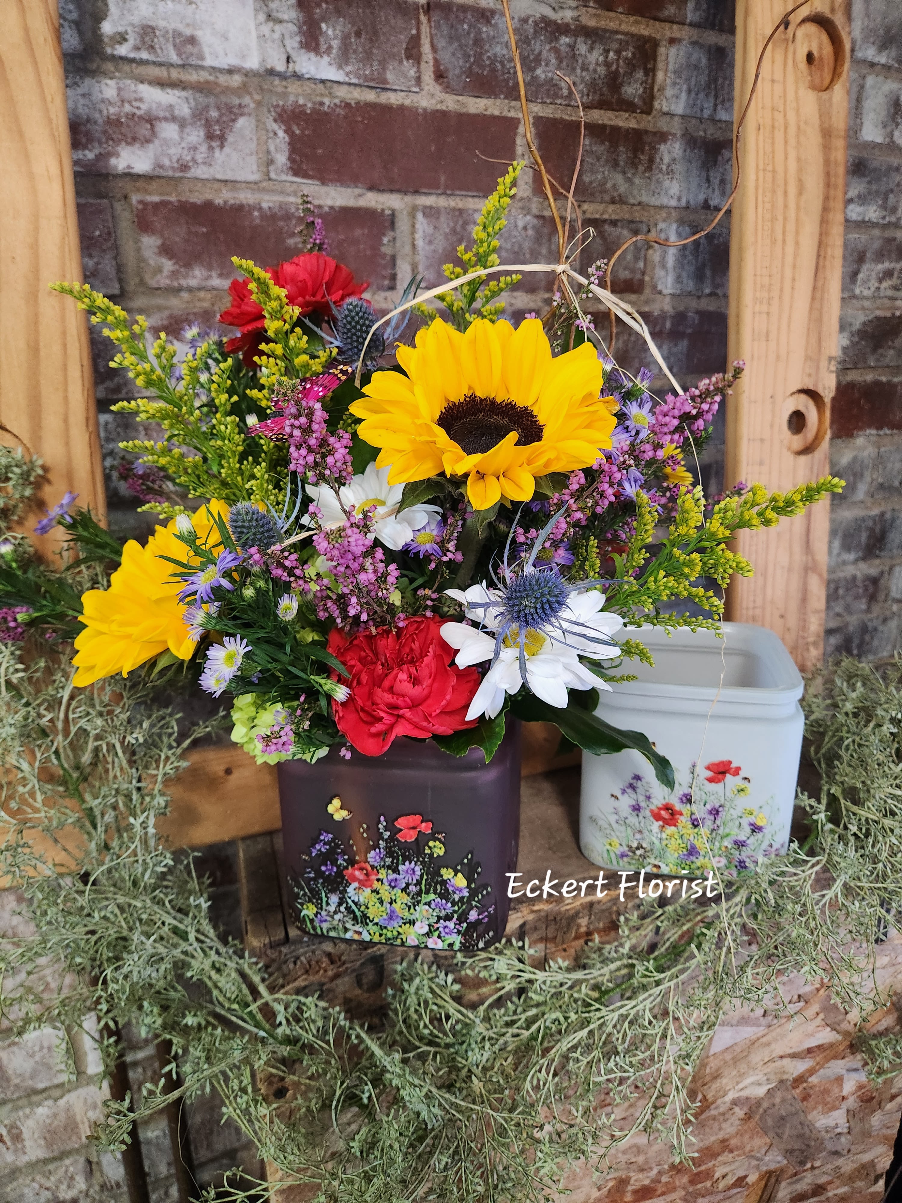 Eckert Florist's Country Cube Bouquet *Our Local Delivery Only - This wonderful wildflower arrangement is full of country charm. Designed in a glass cube with a wild field garden motif, this arrangement is filled with fresh flowers to mimic this feeling. Glass cube measures 4&quot; x 4&quot; x 4&quot;. *Flower variety and cube color may vary. *Our Local Delivery Only