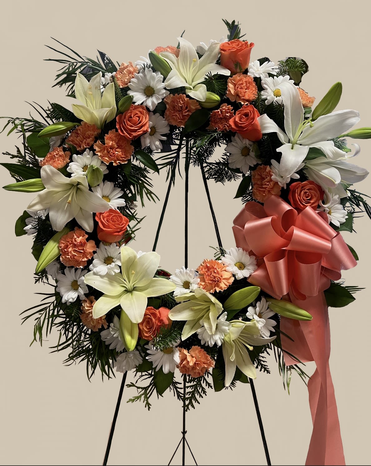 Forever Remembered Wreath - Honor your loved one’s memory with this beautifully crafted funeral wreath. Featuring a harmonious blend of lilies, roses, and daisies, this arrangement symbolizes love, purity, and remembrance.