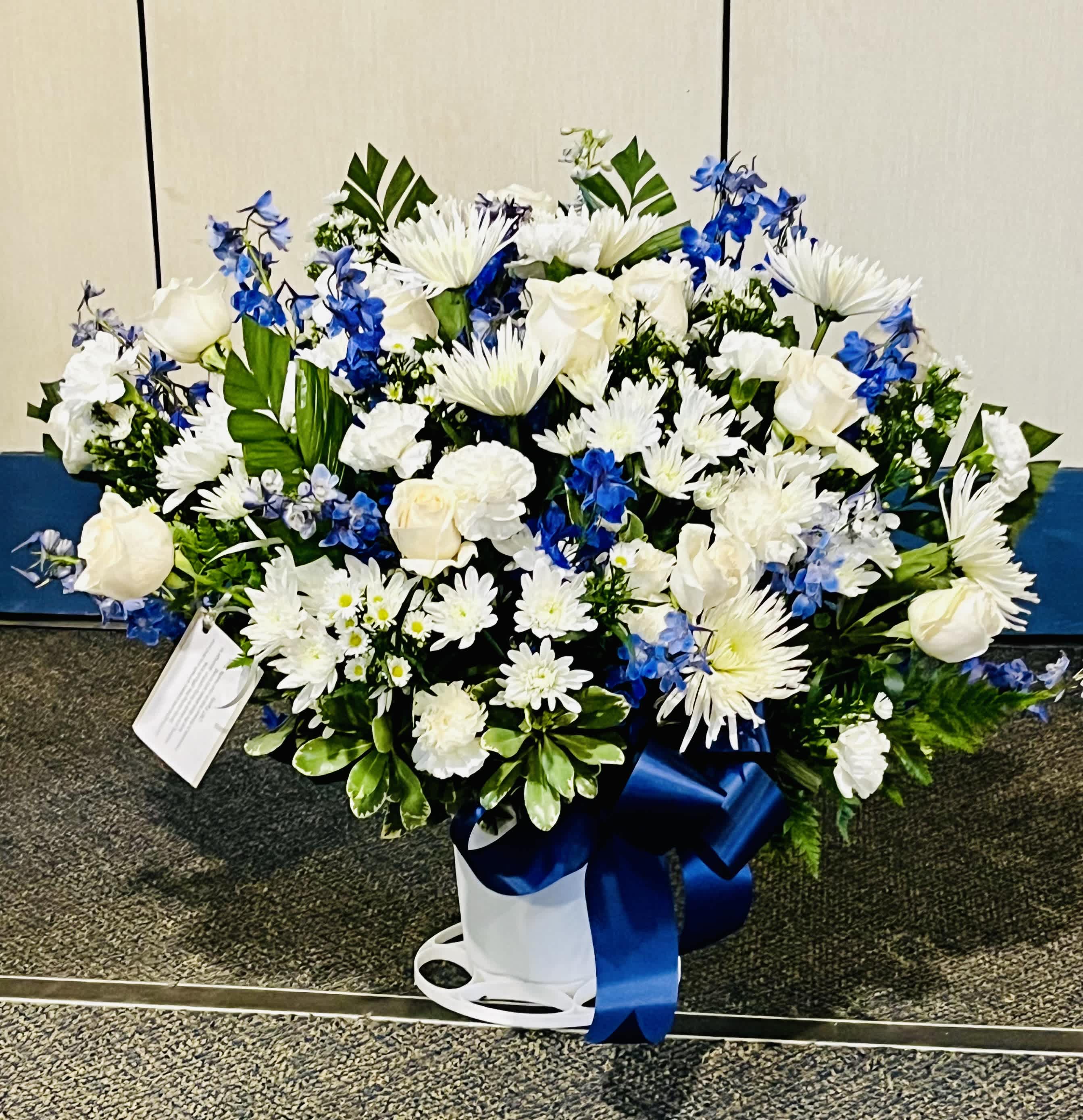 White & Blue Floor Basket by SWF White & Blue Floor Basket by SWF - White Carnations, White Snapdragons, White Cushions, White Montecasino, White Mums, Blue Delphinium with Assorted Greens in Med, Large and Extra Large Available