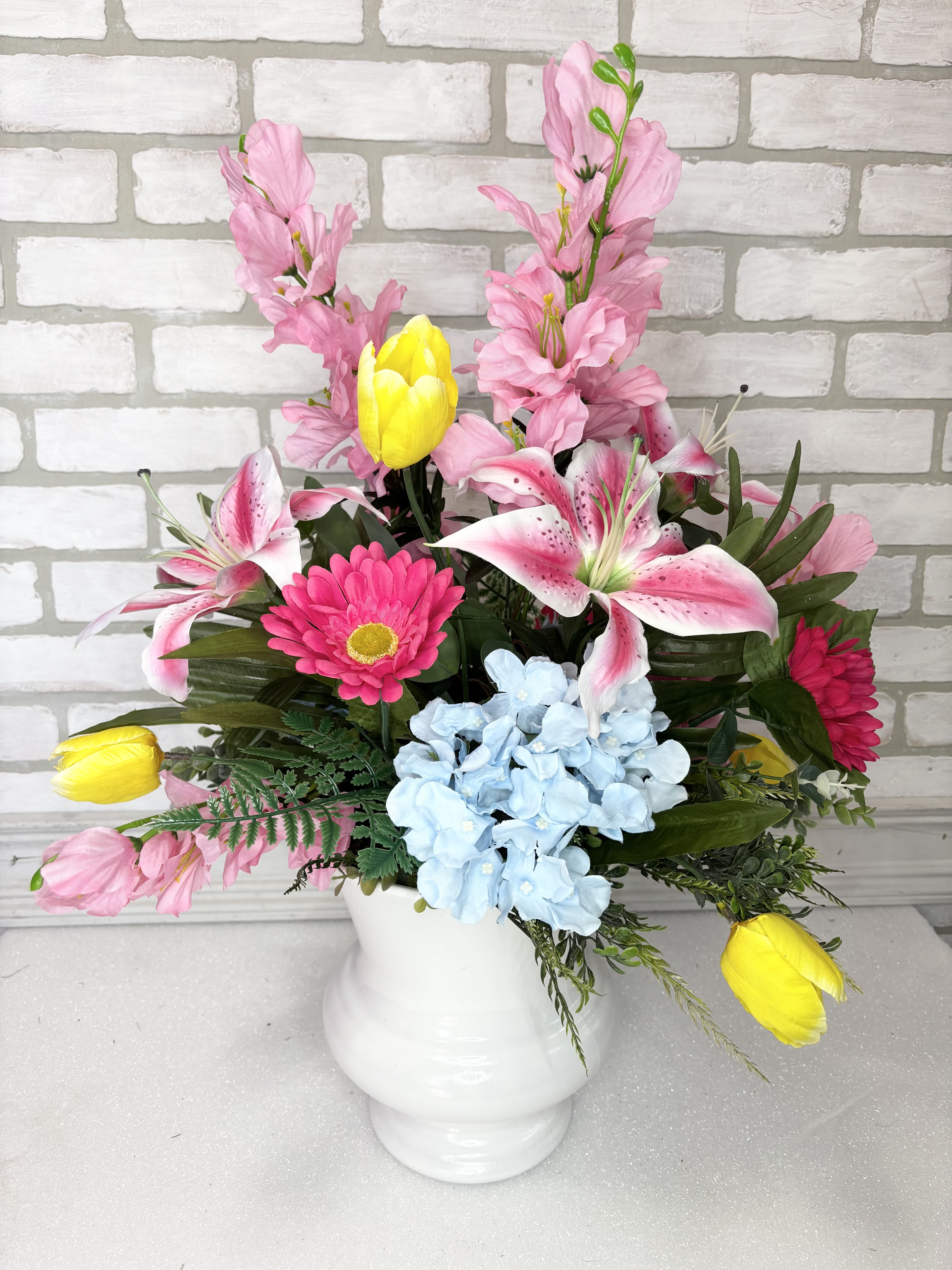 Spring Silk Sympathy Urn - A white urn arranged with silk stargazers, tulips, gerbera daisies, gladiolus, and hydrangea.  