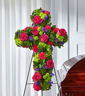 Tribute Rose Floral Cross - For a loved one who lived a faithful life, send prayers and blessings with FTDs' Tribute Rose Floral Cross. A display of vibrant roses stands out among accents of statice, dianthus and button pompons to share your expressions of grace. The arrangement will come with a complimentary metal stand. FTD S5283s  To allow for the freshest blooms, we may substitute for a different variety, color or flower.