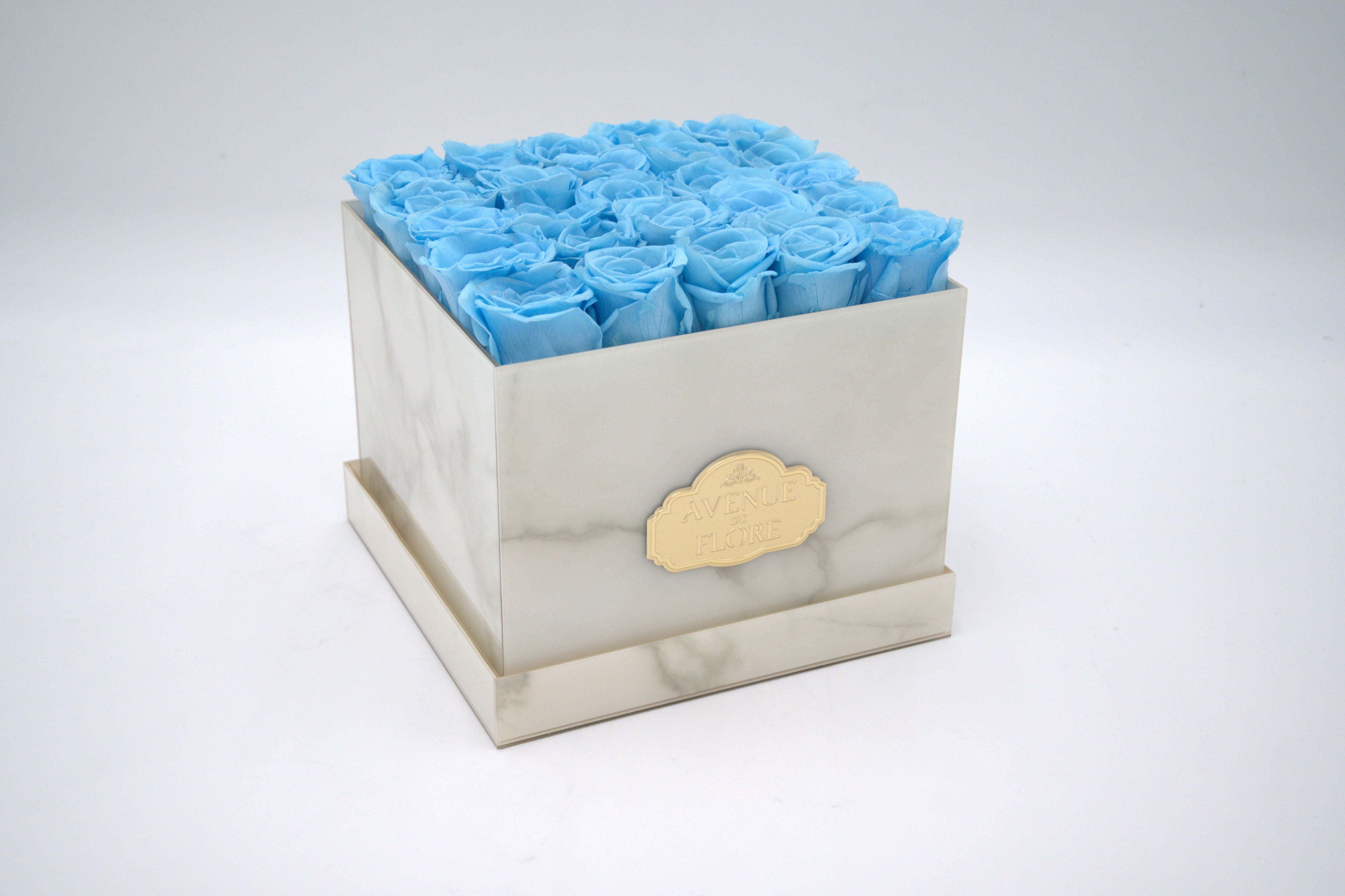 White Marble Square Box - Light Blue Preserved Roses White Marble Square Box - Light Blue Preserved Roses - Discover timeless elegance with our exquisite White Marble box adorned with 25 blue roses. The sleek white marble exterior enhances any space, while the meticulously crafted blue roses gracefully last for years in all their magnificence. Perfect as a unique gift or a statement piece for your home decor. PRESERVED ROSES. NOTE: The shade and size of blue roses may vary slightly from the image, depending on availability.