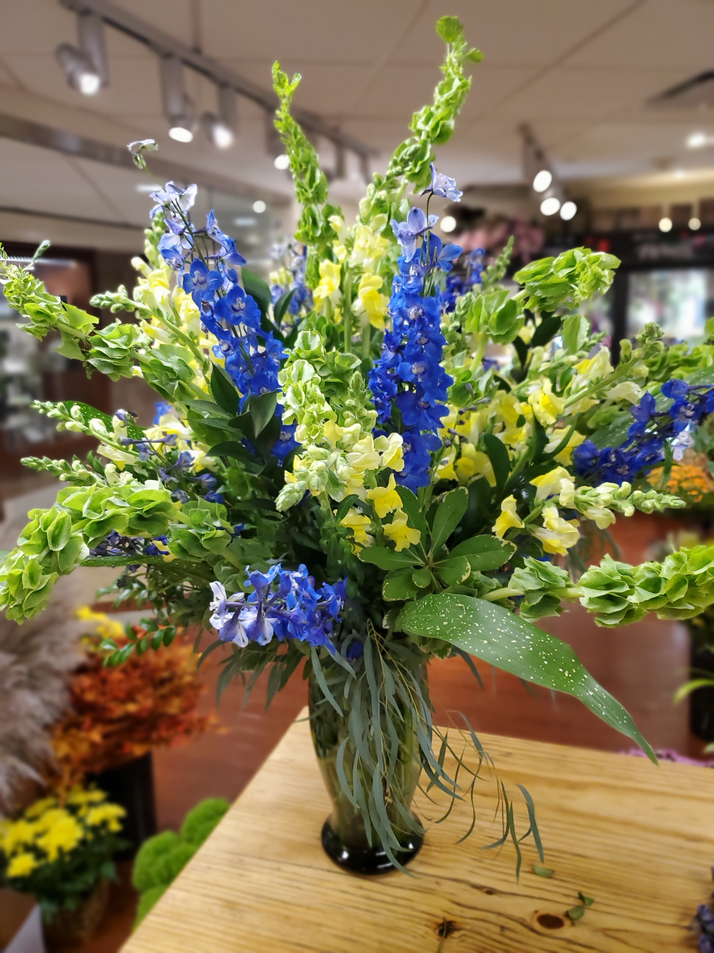 Large Notre Dame Vase - A Large vase filled with Delphinium,  Bells of Ireland, Yellow Snapdragons, and lush greenery. 