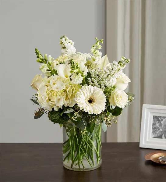 Comforting Thoughts - Celebrate the life of a loved one with our beautiful floral tribute. A gathering of all-white blooms, featuring unique varieties like hydrangeas and mini calla lilies, is accented by lush greenery for an elegant presentation. Designed in a clear glass vase, it’s a special way to honor their memory, while comforting family and friends. More details  All-around arrangement with white hydrangeas, mini white calla lilies, roses, Gerbera daisies, larkspur, snapdragons, stock and Queen Anne’s lace; accented with seeded eucalyptus and assorted greenery