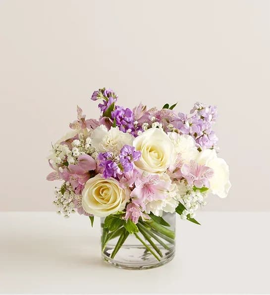 Lovely Lavender  - Lovely memories are made with thoughtful gifts for the ones we care about. Our charming lavender flower bouquet is loosely gathered with a medley of lavender &amp; white blooms. Hand-designed inside a clear cylinder vase with cascading greenery all around, it’s a wonderful way to express the sentiments you have inside your heart. More details  All-around arrangement with white roses and carnations; lavender Peruvian lilies (alstroemeria) and stock; accented with baby’s breath and assorted greenery