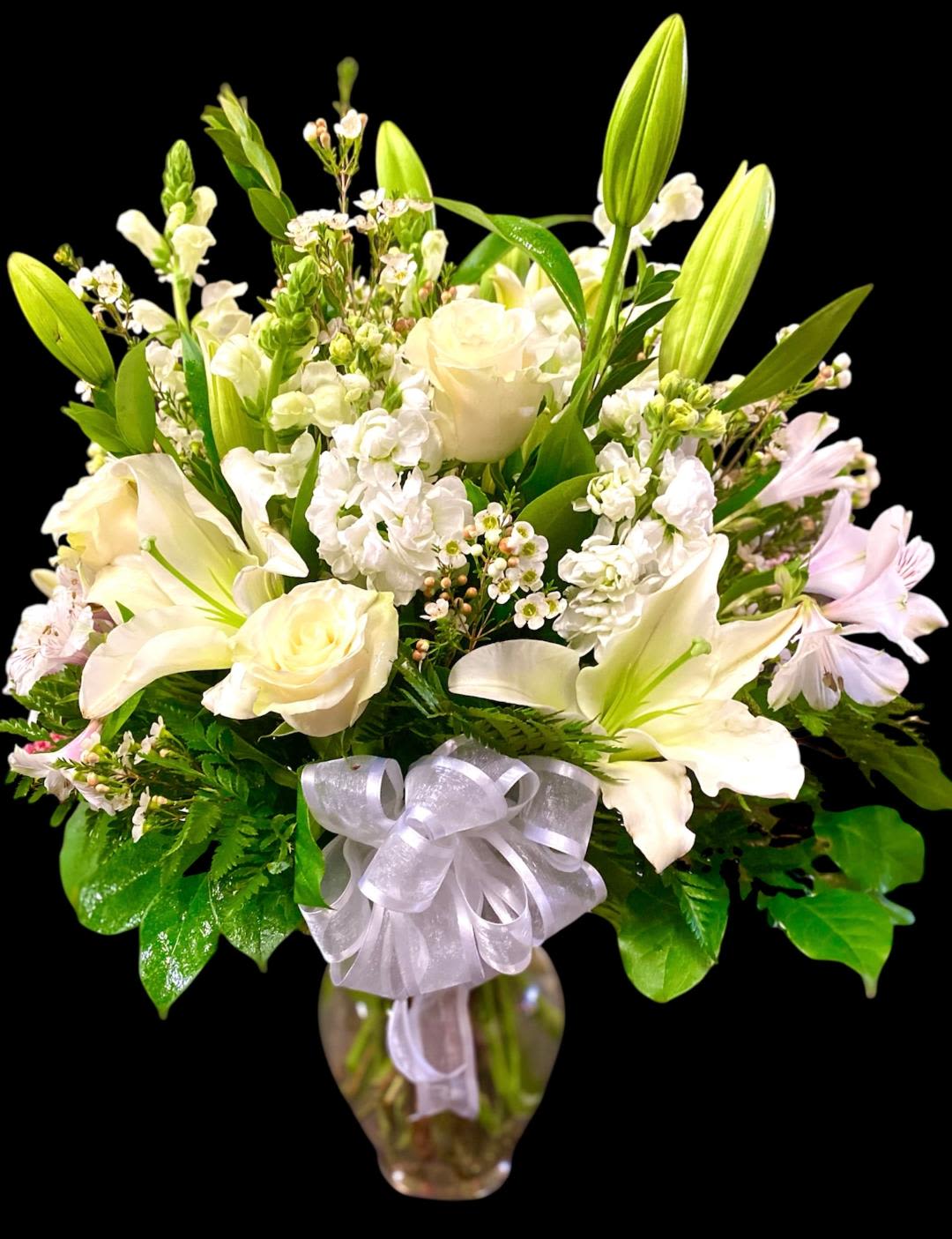 Pure Serenity Pure Serenity - This full lush design includes a variety of white premium blooms to provide the perfect sentiment for just about any occasion. This design includes Roses, Lilies, Snapdragons, Stock, Alstroemeria, and Carnations. These blooms are arranged in a ginger vase and accented with various types of foliage, finished with a chiffon bow. This design measures approx. 18 "W x 21"H.