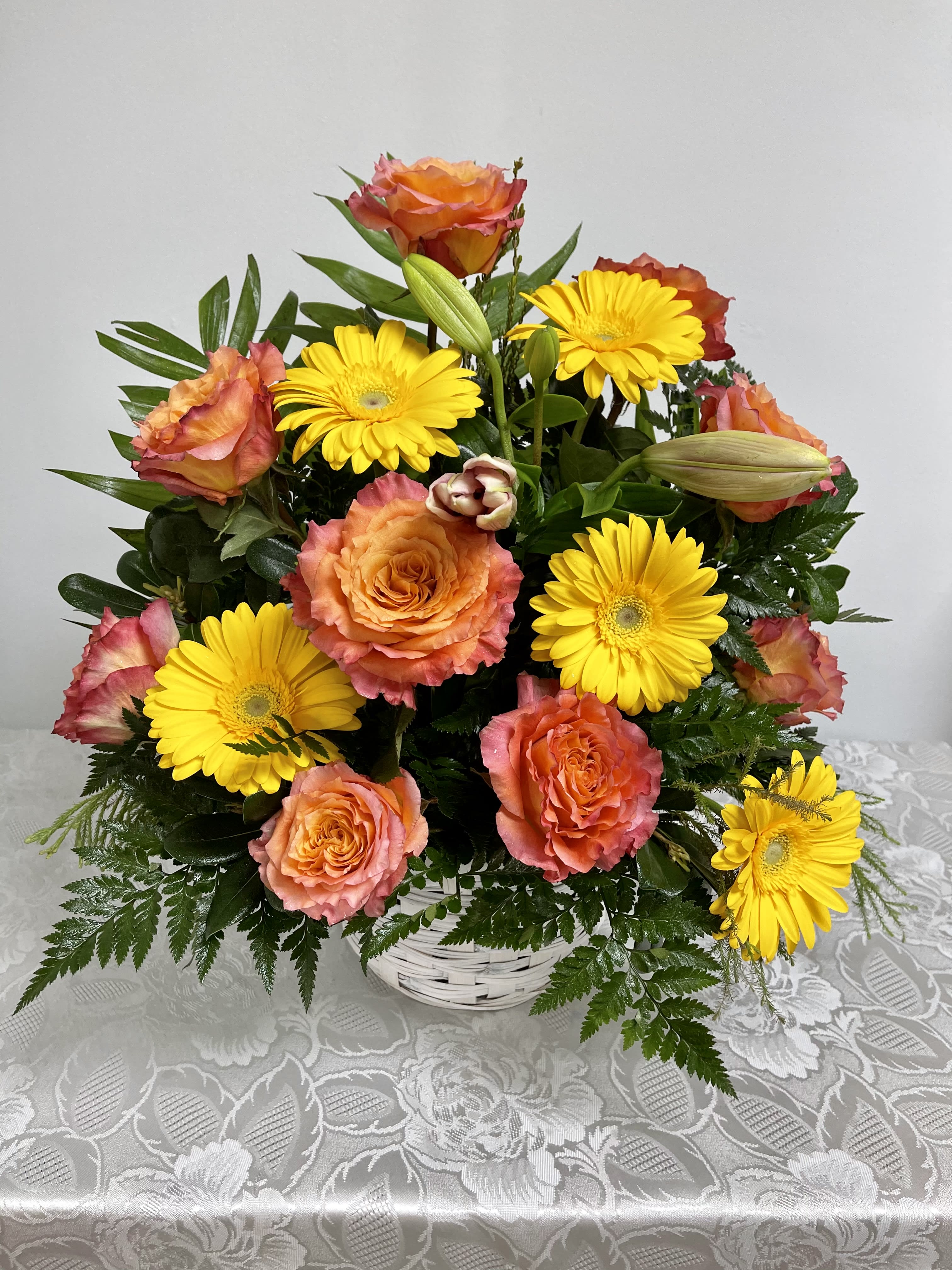 Forever Spirit - A peach, yellow, and pink funeral basket for any type of service. Held in a white basket, baker ferns line the bottom and gives a natural spotlight for the feature blooms and colors.
