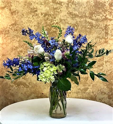 Midnight Midnight - What to make a statement? This is just the gift to send. Beautiful Blue Delphinium, Mini green hydrangeas, White rose designed with beautiful greens in a clear glass vase.