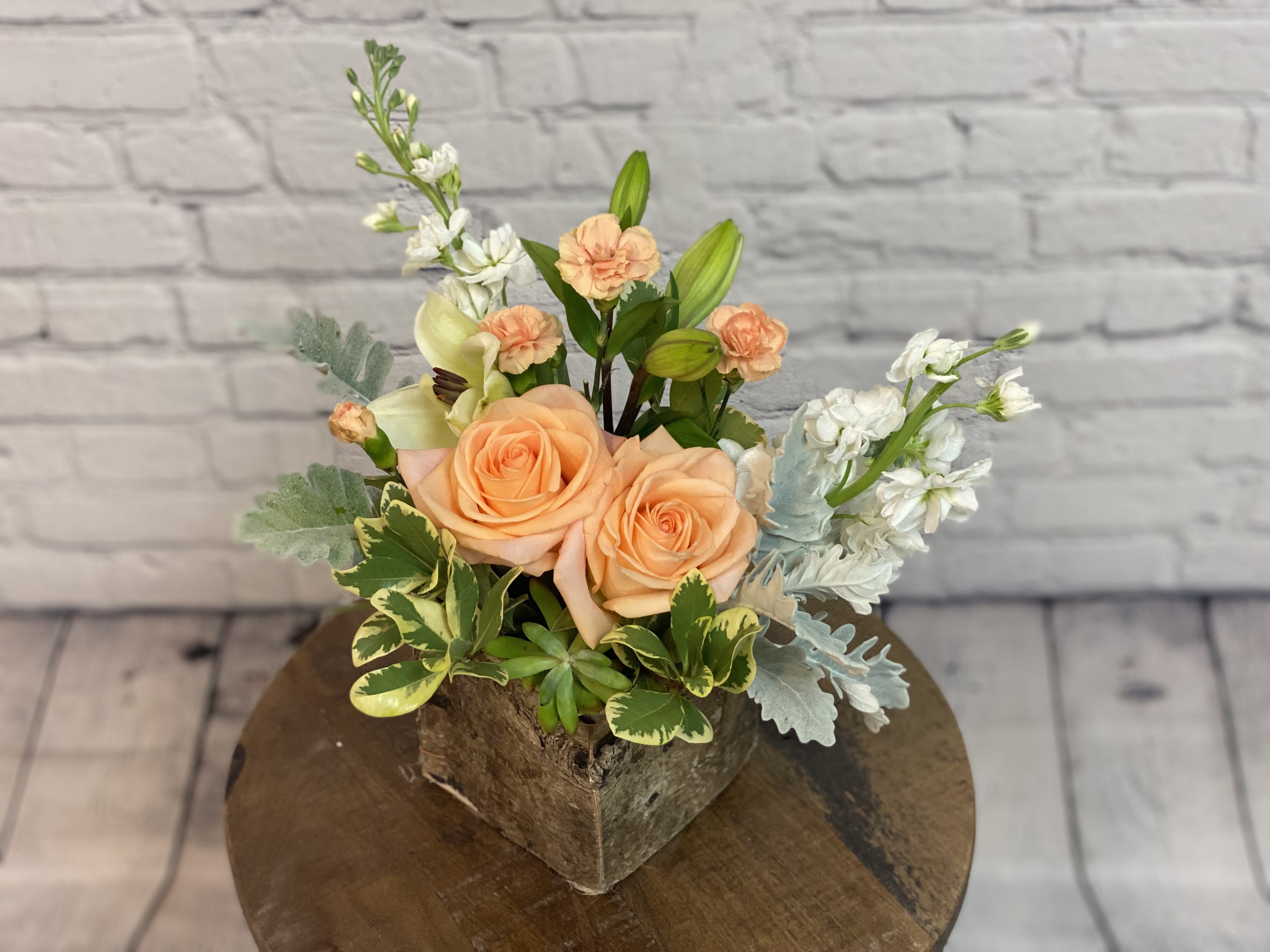 Southern Peach Bouquet - Looking for a modern twist on an old classic - this bouquet is just what you need! The Southern Peach Rose Bouquet brings you a subtle and sophisticated look with a bit of modern style. Charming and easy on the eyes, with beautiful pastel tones, this bouquet brings a room to life with it's artful appearance. Peach roses surrounded by white lilies, peach carnations and greenery - but the best part? All of this surrounds a green echeveria succulent. The fun new accessory to any bouquet, this delicate succulent adds a modern touch and is guaranteed to delight! This bouquet measures 15 1/4&quot; W by 13 1/4&quot; H