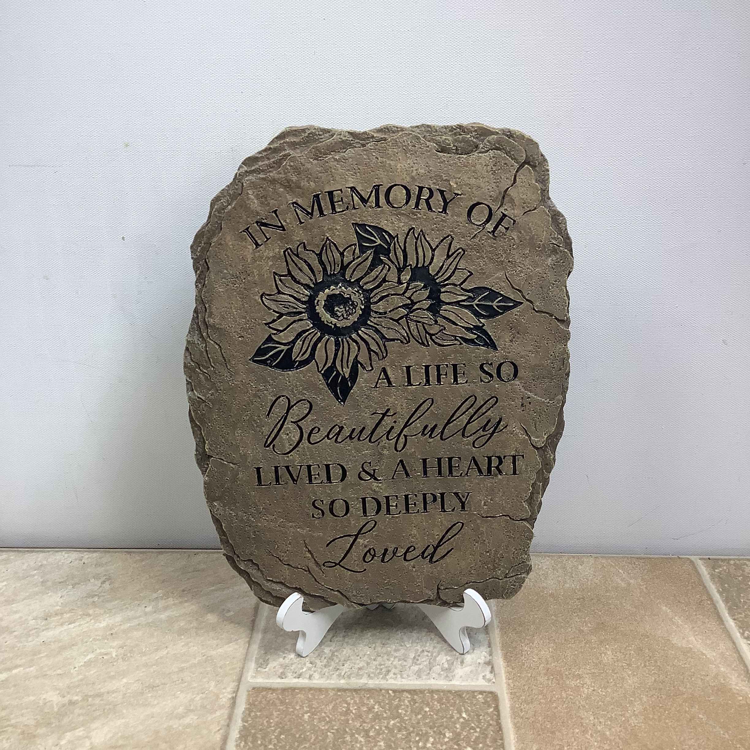 Stepping stone - In Memory of a Life Stepping stone - In Memory of a Life - Our memorial garden stones serve as a touching tribute to honor those who have passed. Express your condolences with this polyresin stepping stone featuring the verse “In memory of a life so beautifully lived & a heart so deeply loved”. It measures 8” wide x 10” tall and includes a display easel.