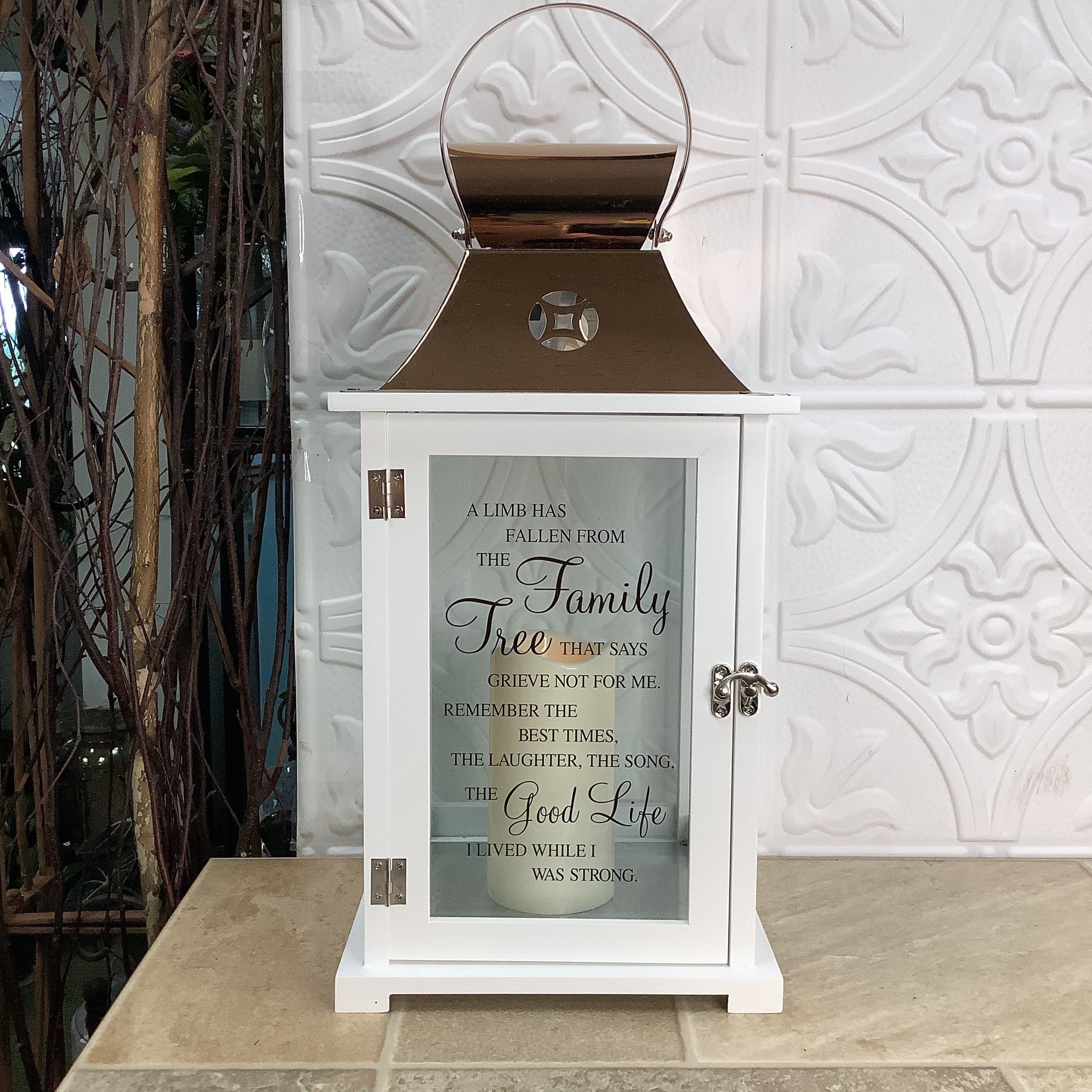 Lantern - Sympathy Lantern - Sympathy - A beautiful white and bronze lantern with a lovely quote on the front and a battery operated candle inside. It measures 9” x 9” x 20”. Quote on the front: “A limb has fallen from the family tree that says grieve not for me. Remember the best times, the laughter, the song, the good life I lived while I was strong. Dimensions: 9” x 9” x 20”
