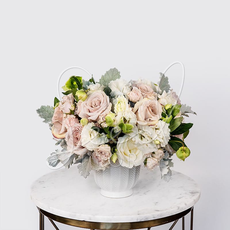 Blush Bliss - Garden Pave Style in a Textured White Vase arranged with a combo of roses in cream, nude &amp; blush, hellebores, dusty miller &amp; cream lisianthus.
