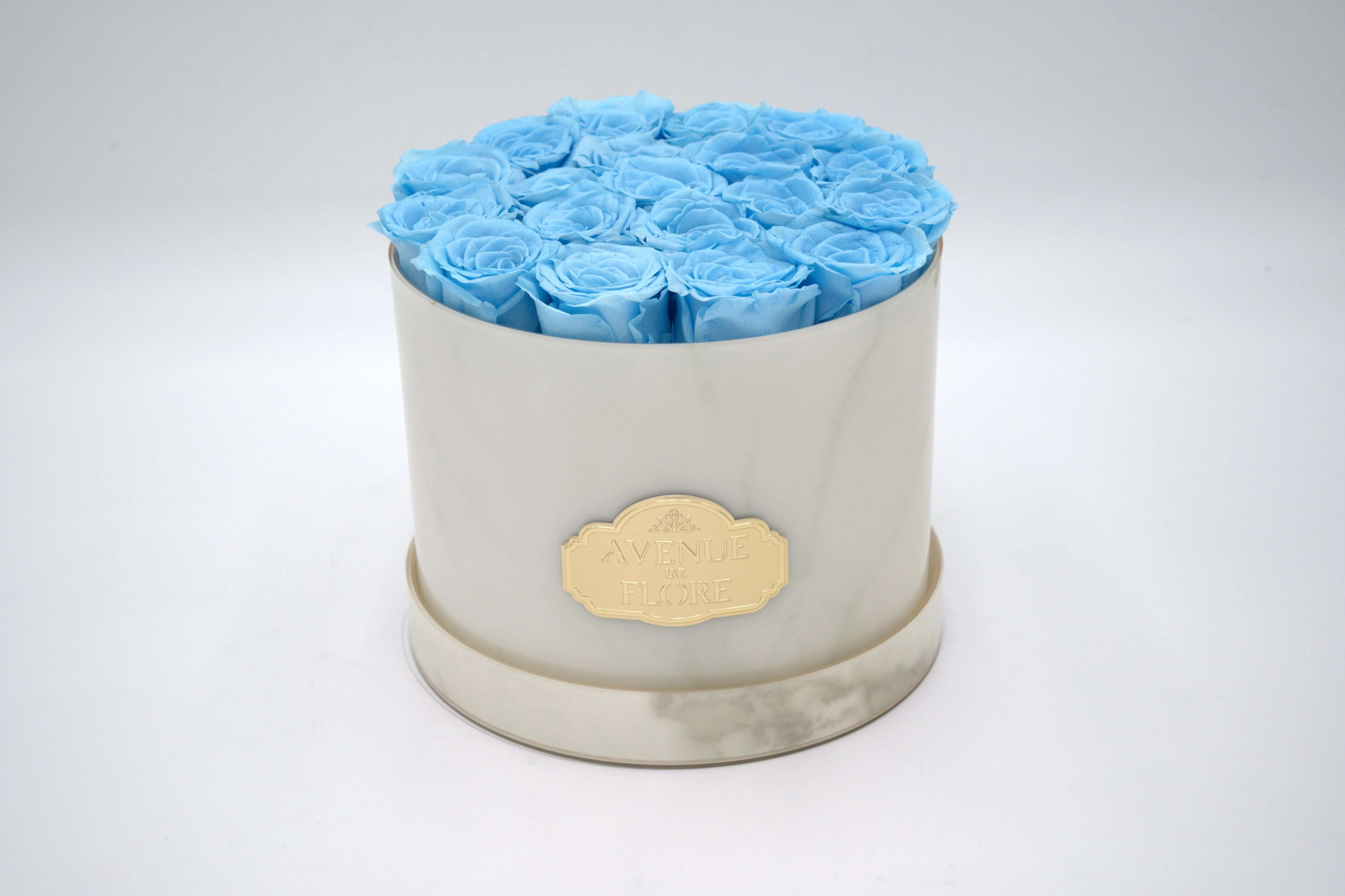 White Marble Round - Light Blue Preserved Roses - PRESERVED ROSES. Discover timeless elegance with our exquisite White Marble box adorned with 15 blue roses. The sleek white marble exterior enhances any space, while the meticulously crafted blue roses gracefully last for years in all their magnificence. Perfect as a unique gift or a statement piece for your home decor.   NOTE: The shade and size of blue roses may vary slightly from the image, depending on availability. 