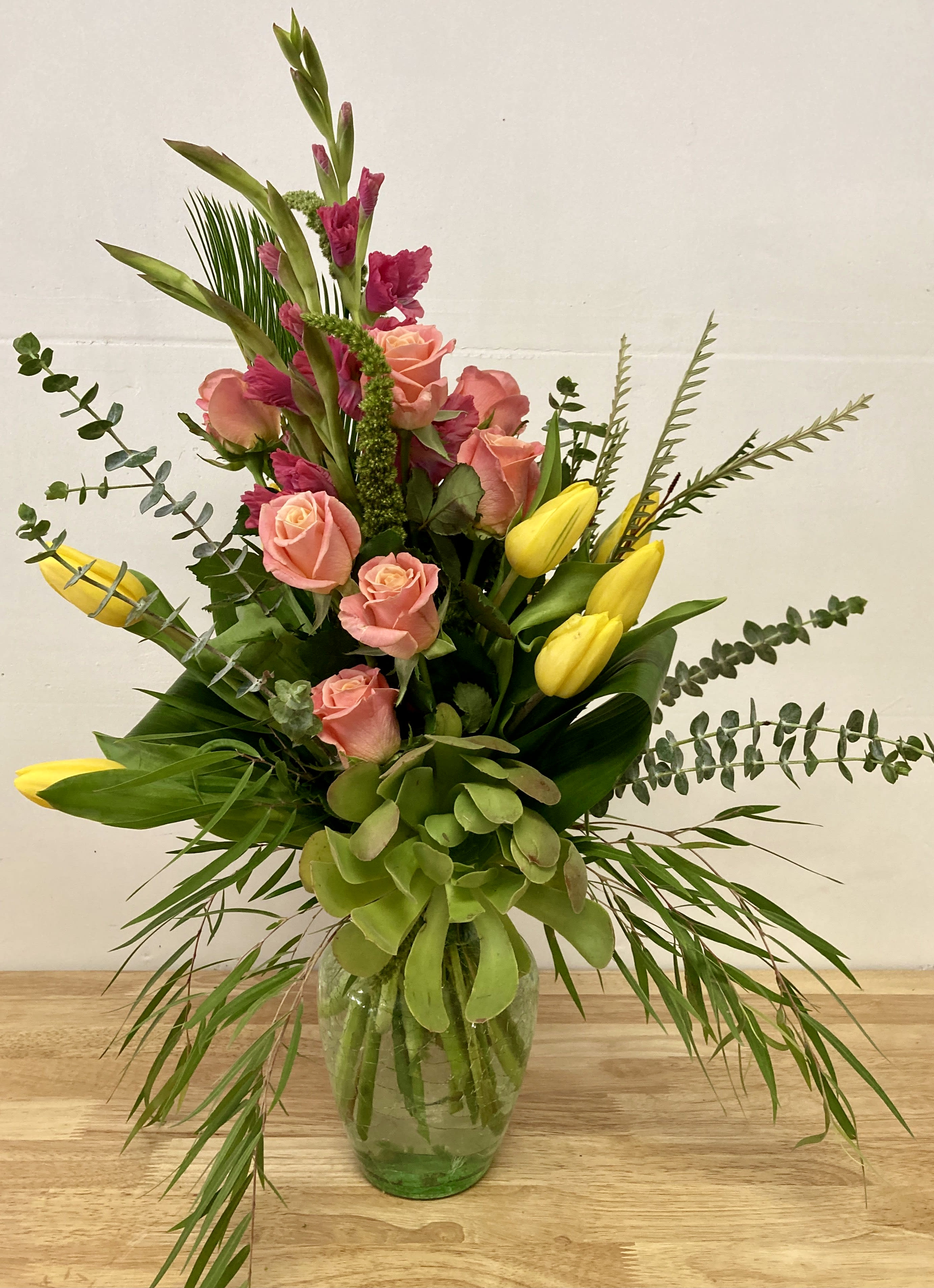 Burst of Spring Burst of Spring - Vibrant, impressive display of locally sourced seasonal blooms.Welcome the warmth and hope of Spring with this beautiful display spring colored flowers. Roses, tulips, gladiolas and succulents fill this cylinder vase making it a great size for a beautiful kitchen or bathroom display.