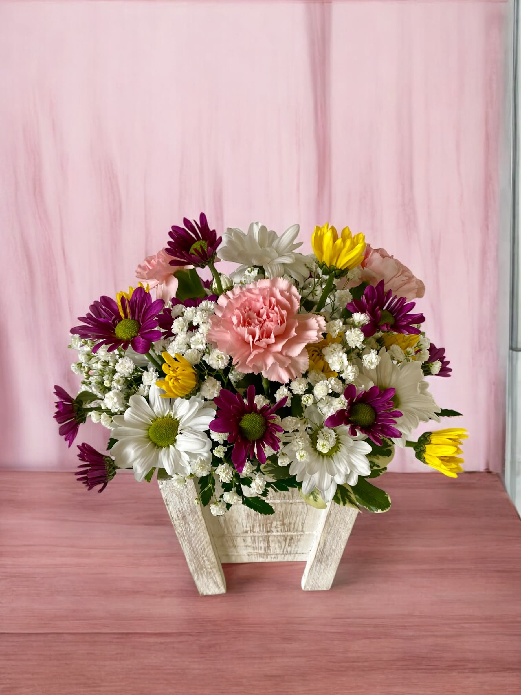 Country Meadows - This sweet arrangement is designed in a whitewashed wooden container and includes our freshest daisies, carnations, miniature carnations, poms and complimentary filler flowers. The colors and varieties may vary, but the overall look and composition of this arrangement will reflect the one shown.